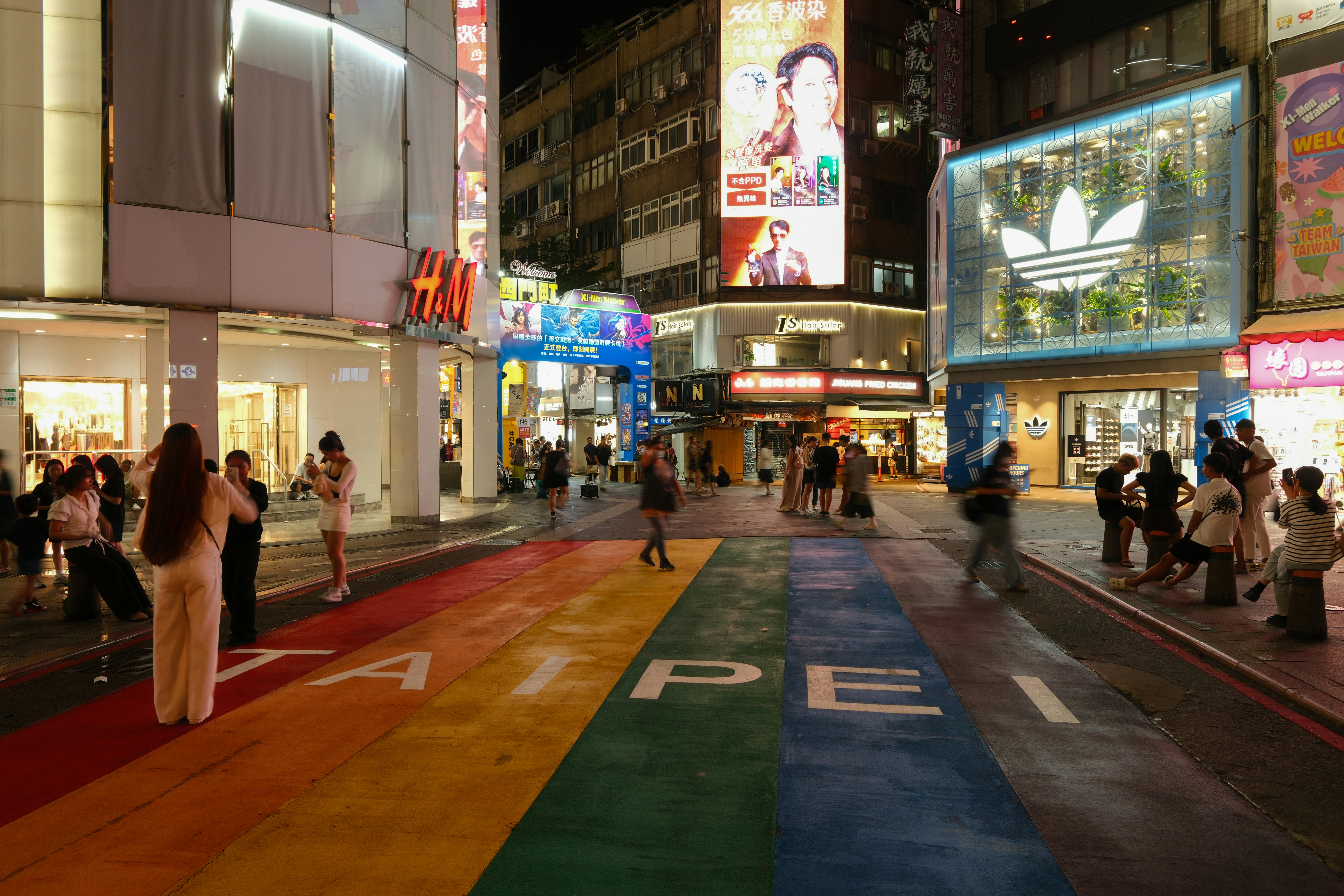 People walking on a rainbow-painted pedestrian street in Ximending, Taipei, at night