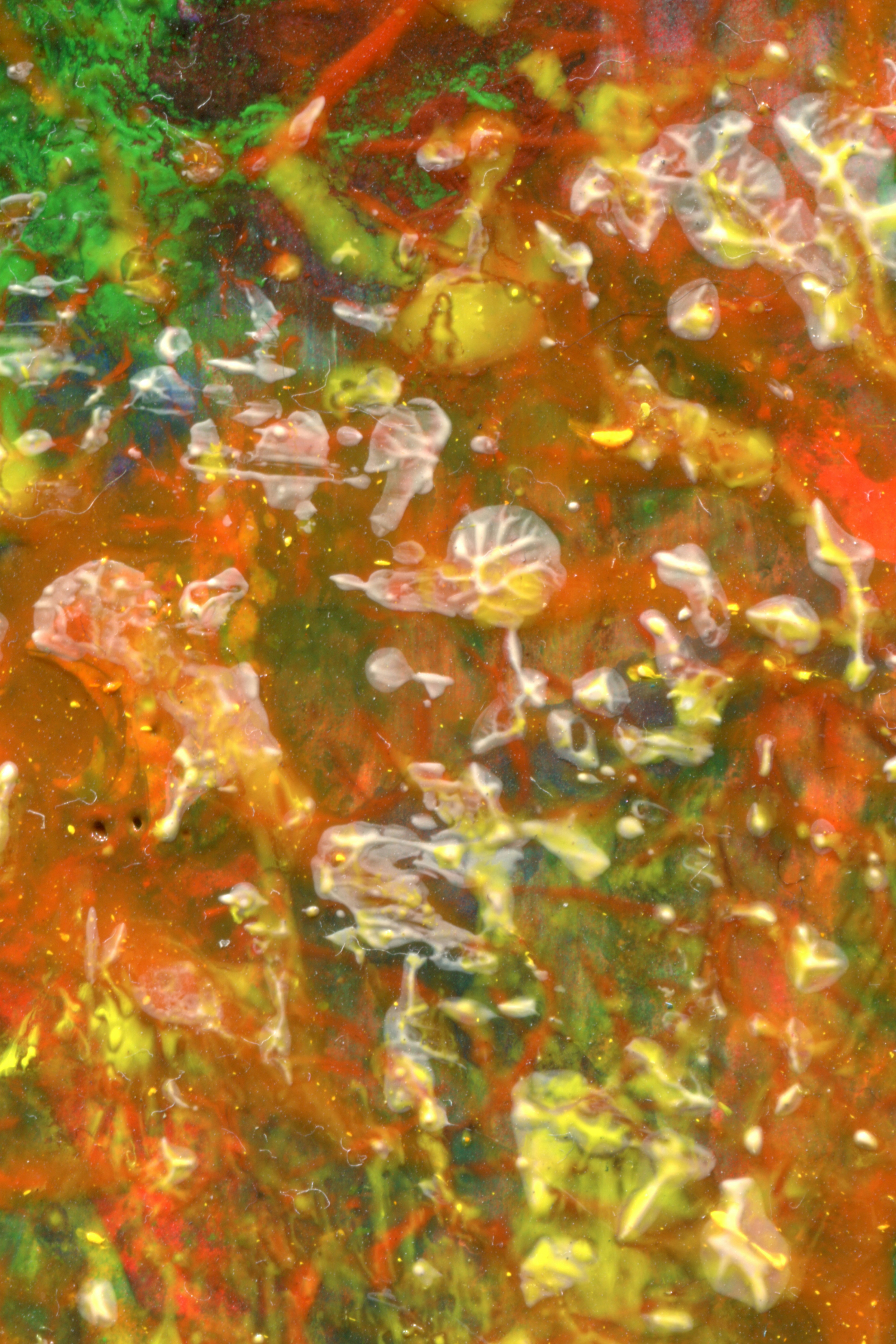 Abstract swirls of vibrant red, green, and yellow paint with raised translucent droplets