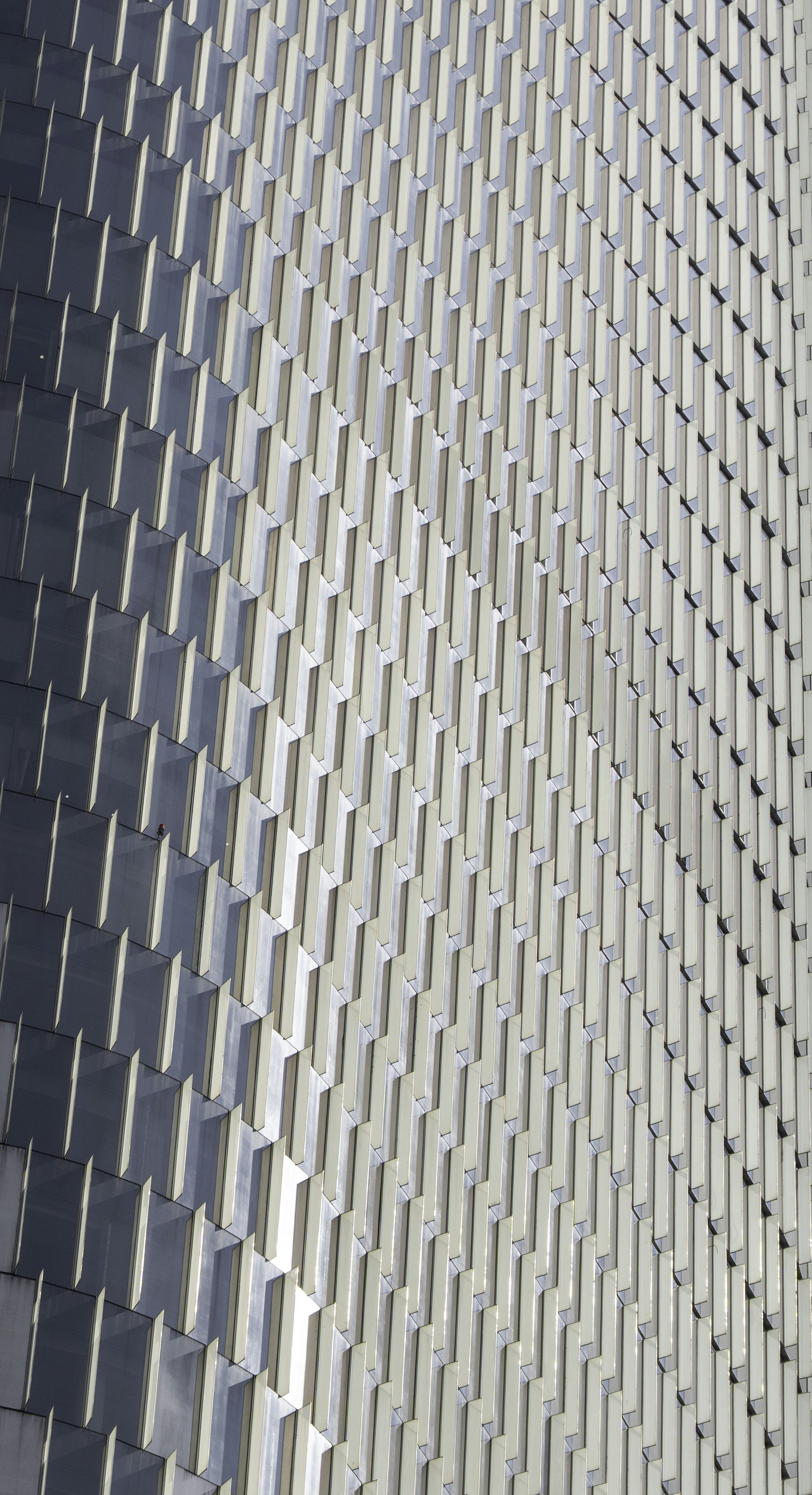 A repeating pattern of glass windows and vertical white fins on a modern skyscraper facade