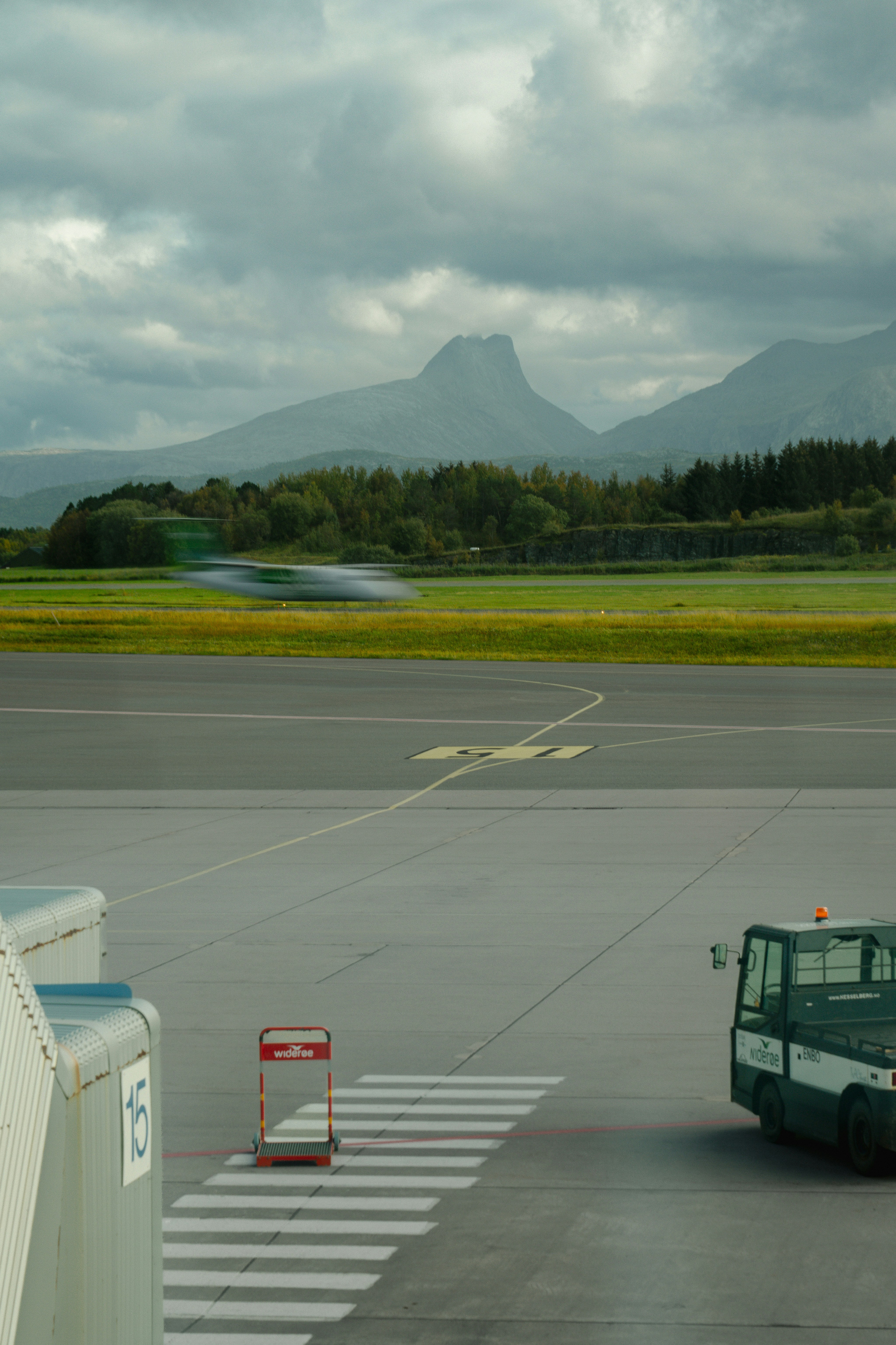 Un aereo sfocato che decolla da una pista di aeroporto con montagne sullo sfondo
