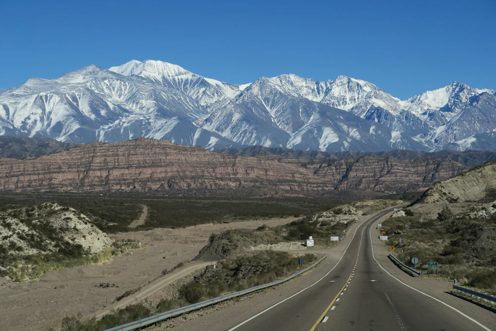 Carretera recta hacia la cordillera nevada