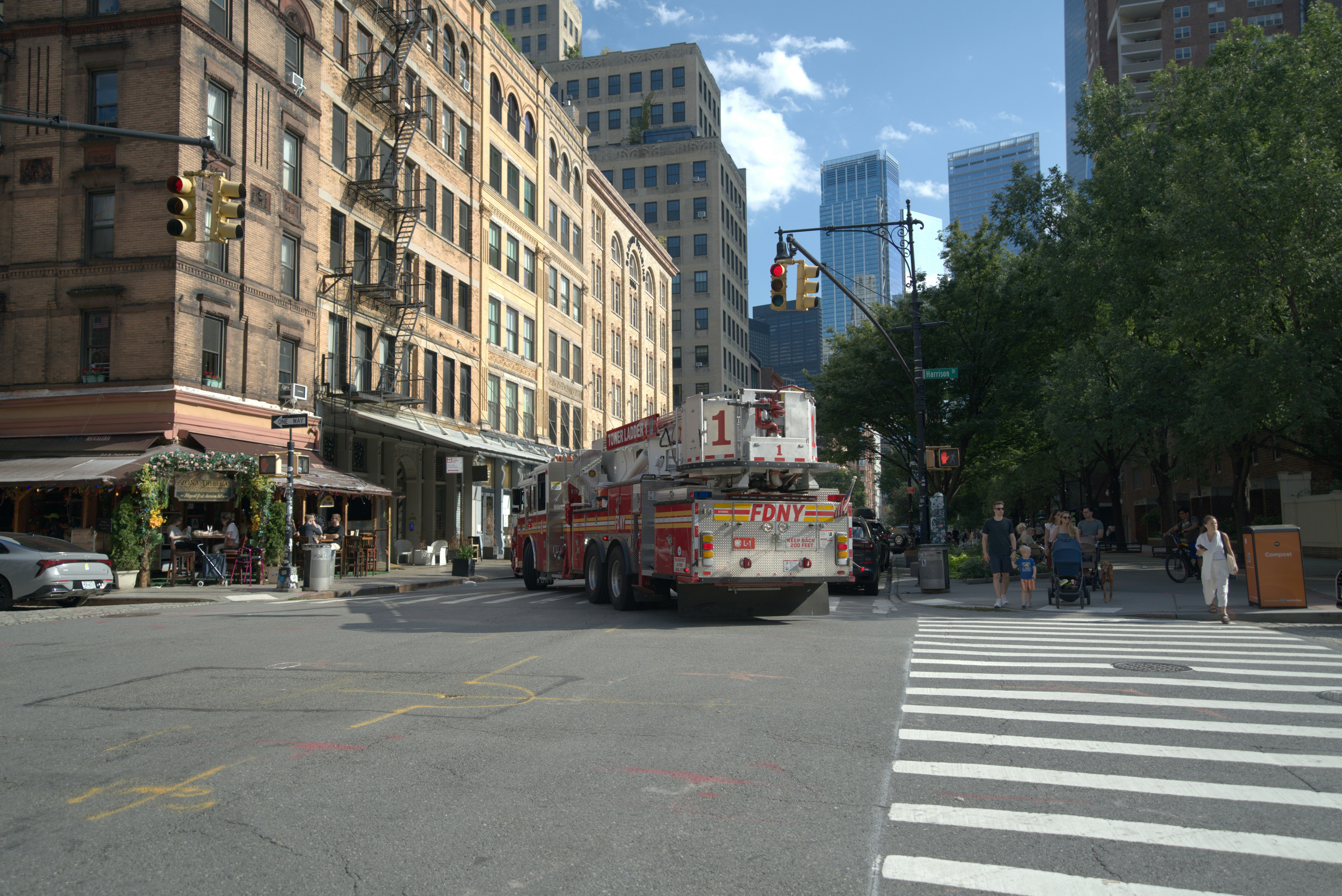 An FDNY fire truck at a city intersection with pedestrians on a crosswalk