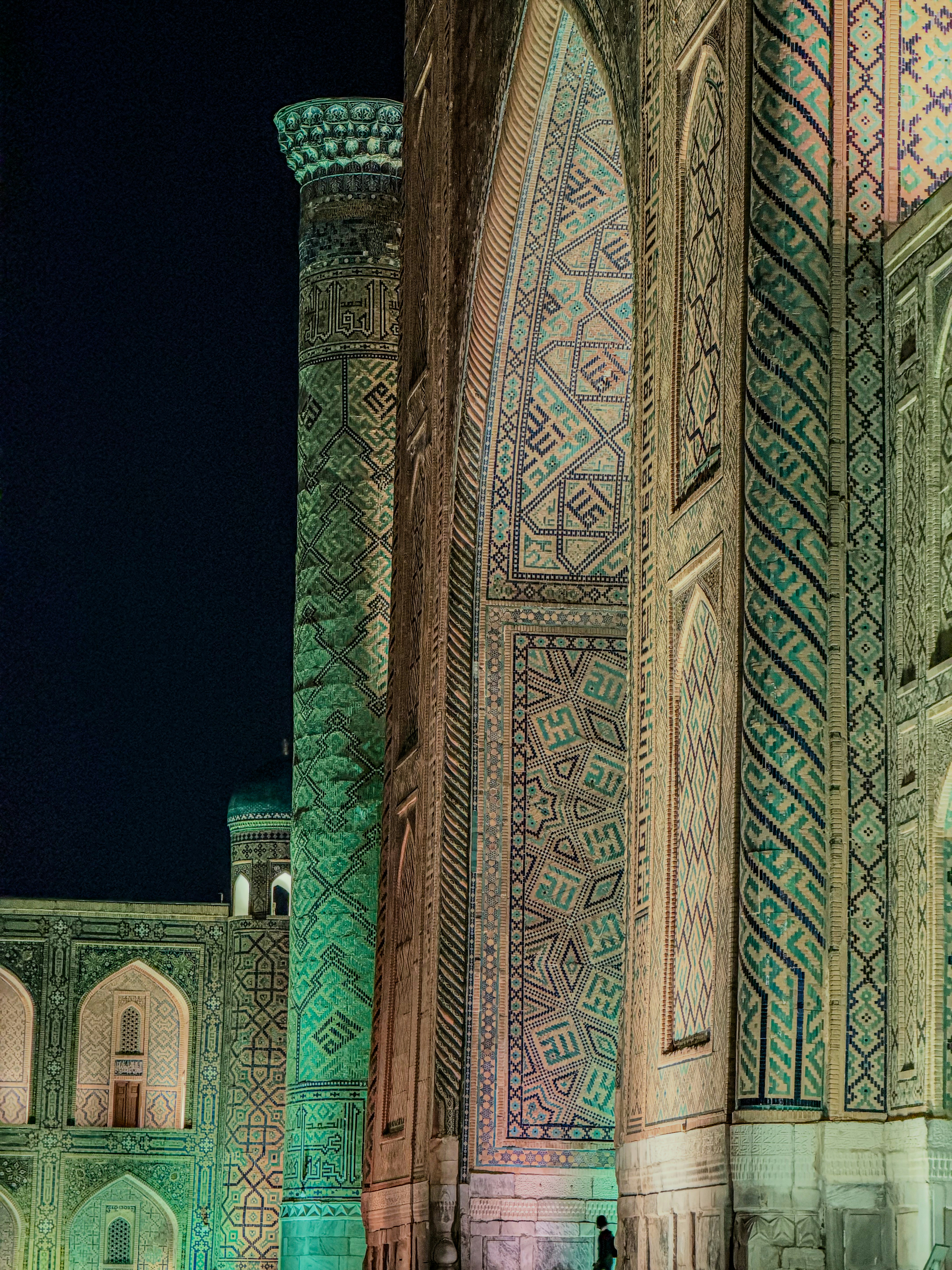 The illuminated tilework of the Registan in Samarkand at night with intricate geometric patterns