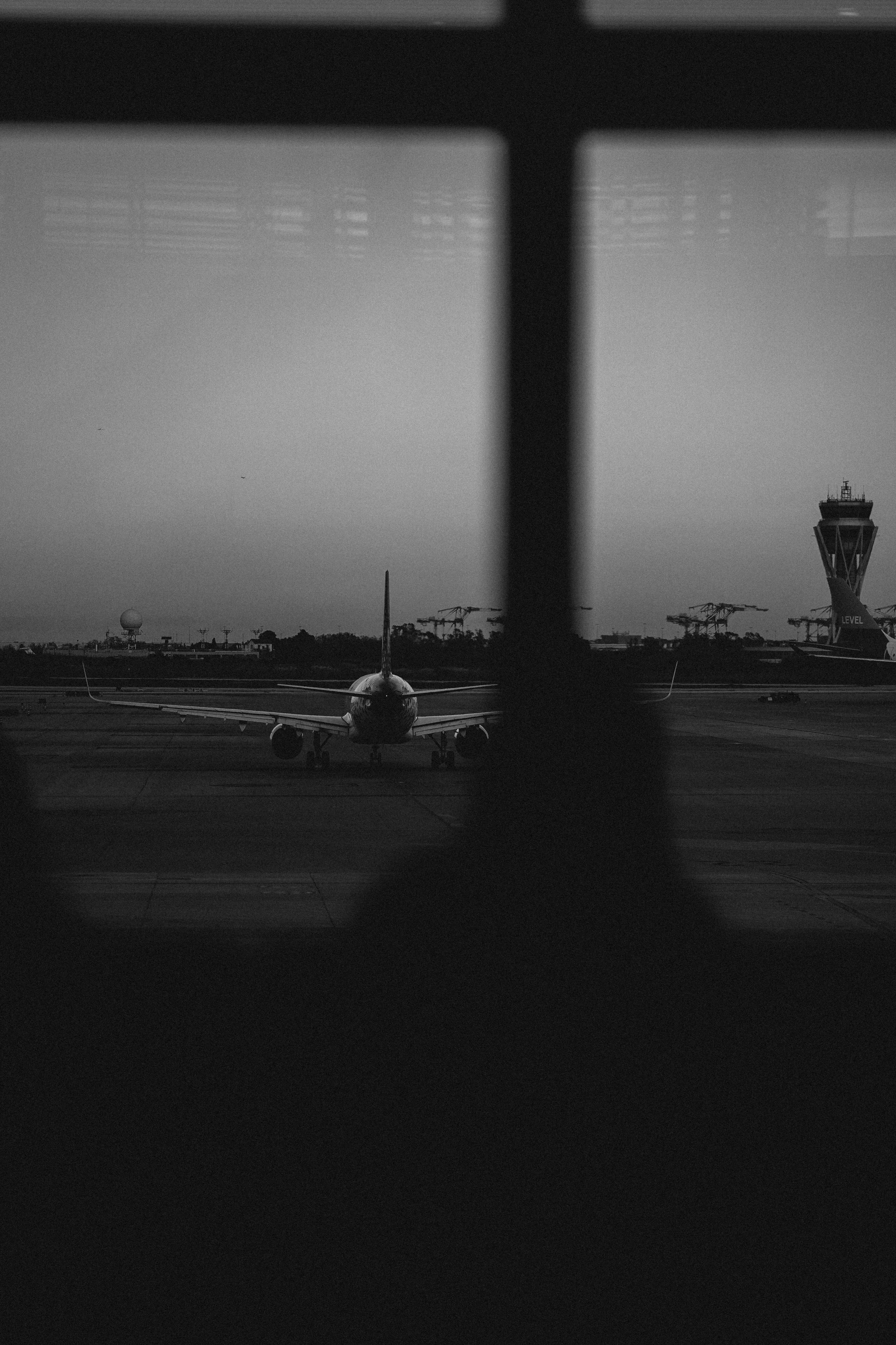 An airplane on the tarmac at an airport seen through a window frame
