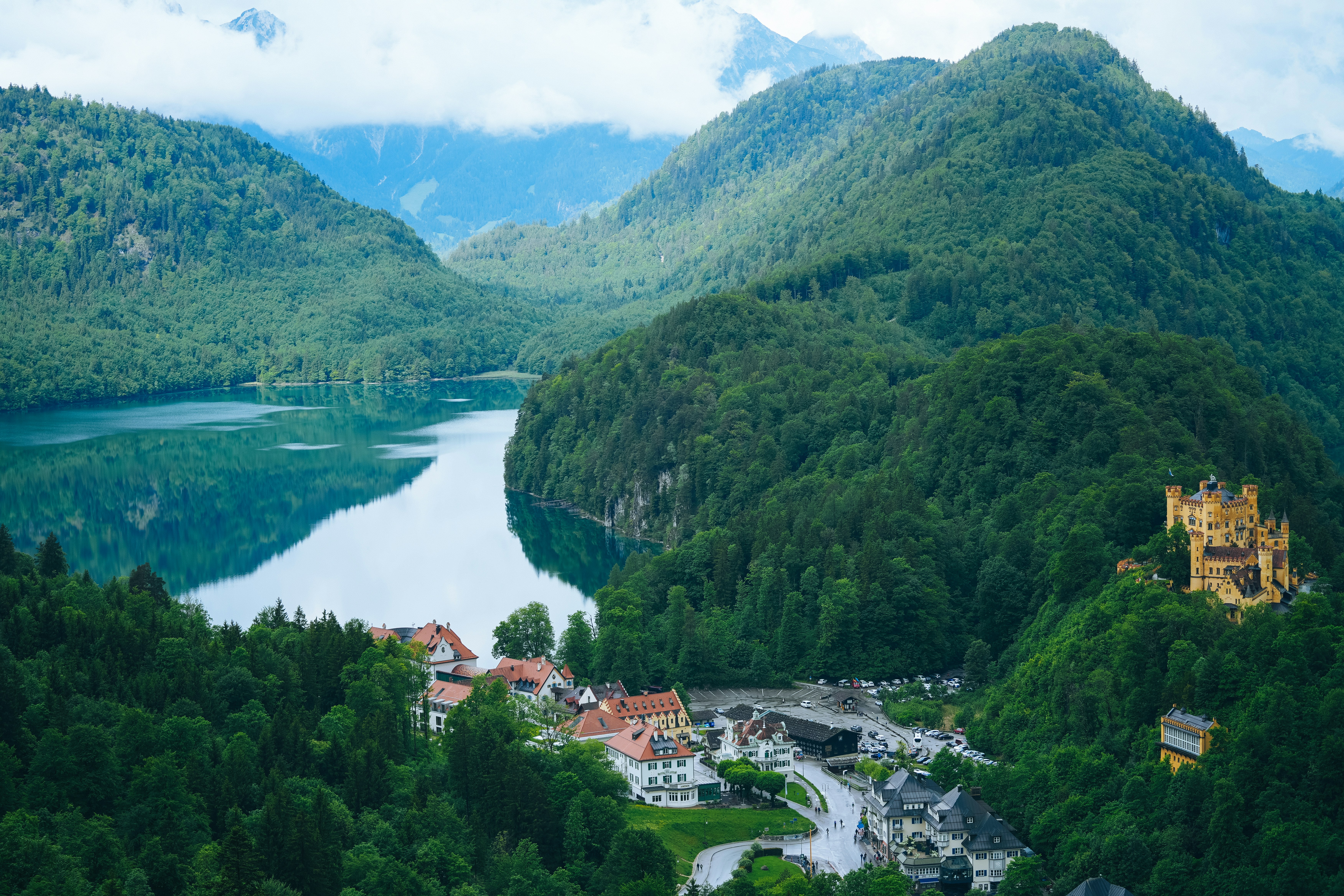 Hohenschwangau Castle overlooking Alpsee lake surrounded by lush green mountains in Bavaria