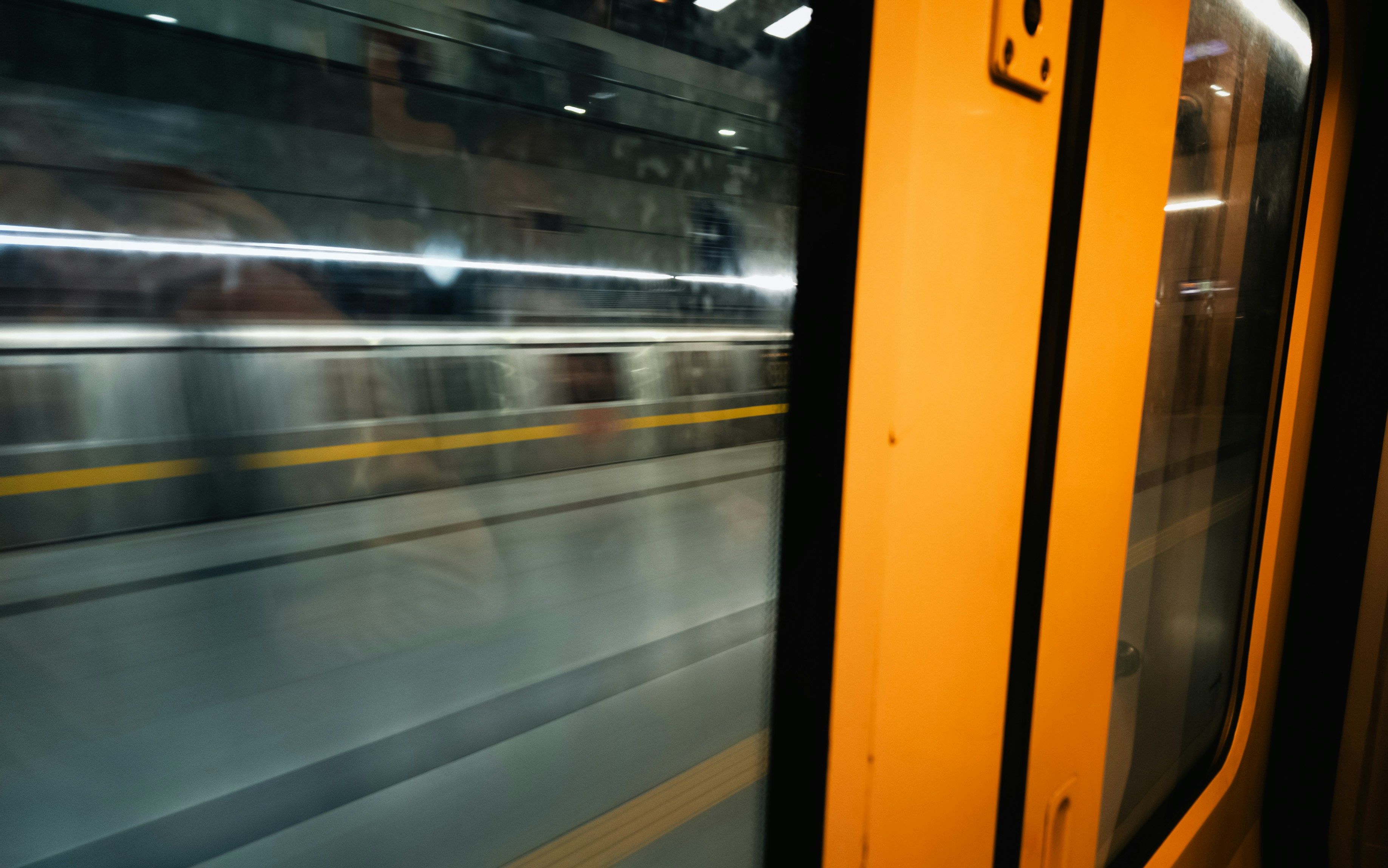 A motion-blurred view of a subway train passing through a station in Delhi