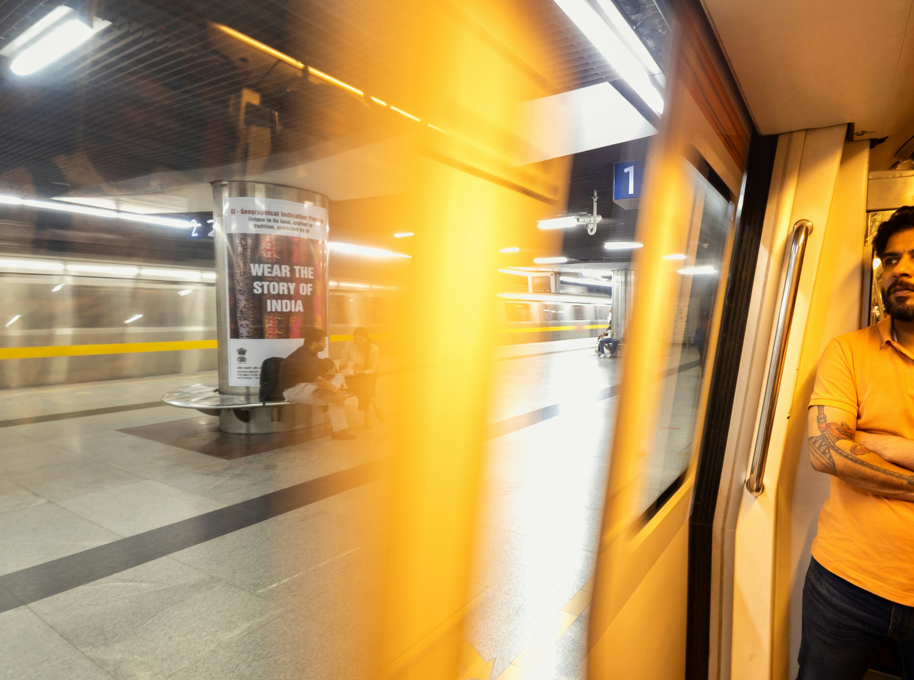 A person in an orange shirt inside a subway train looking at a station platform