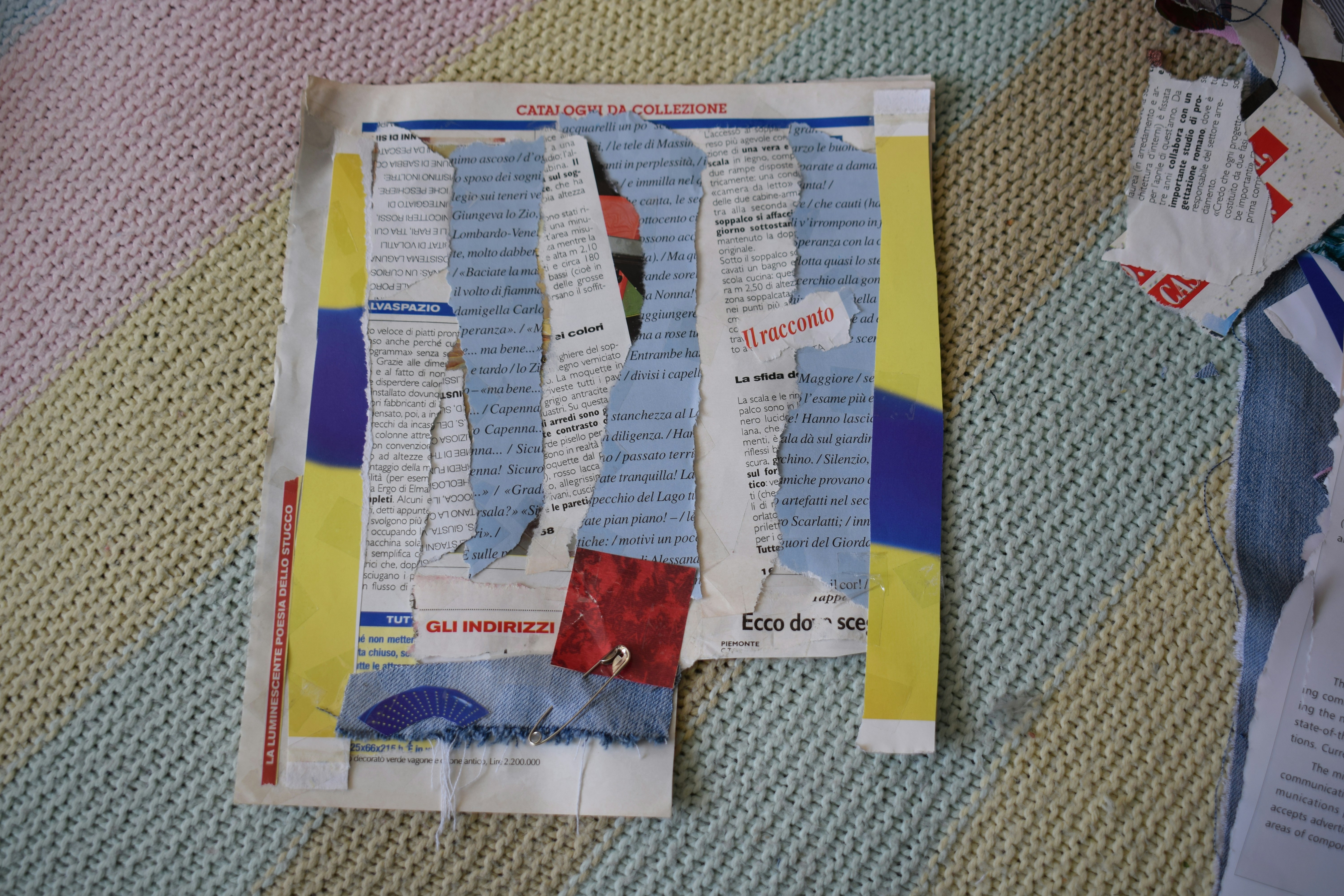 A collage of torn newspaper clippings and fabric scraps on a textured pastel knit background