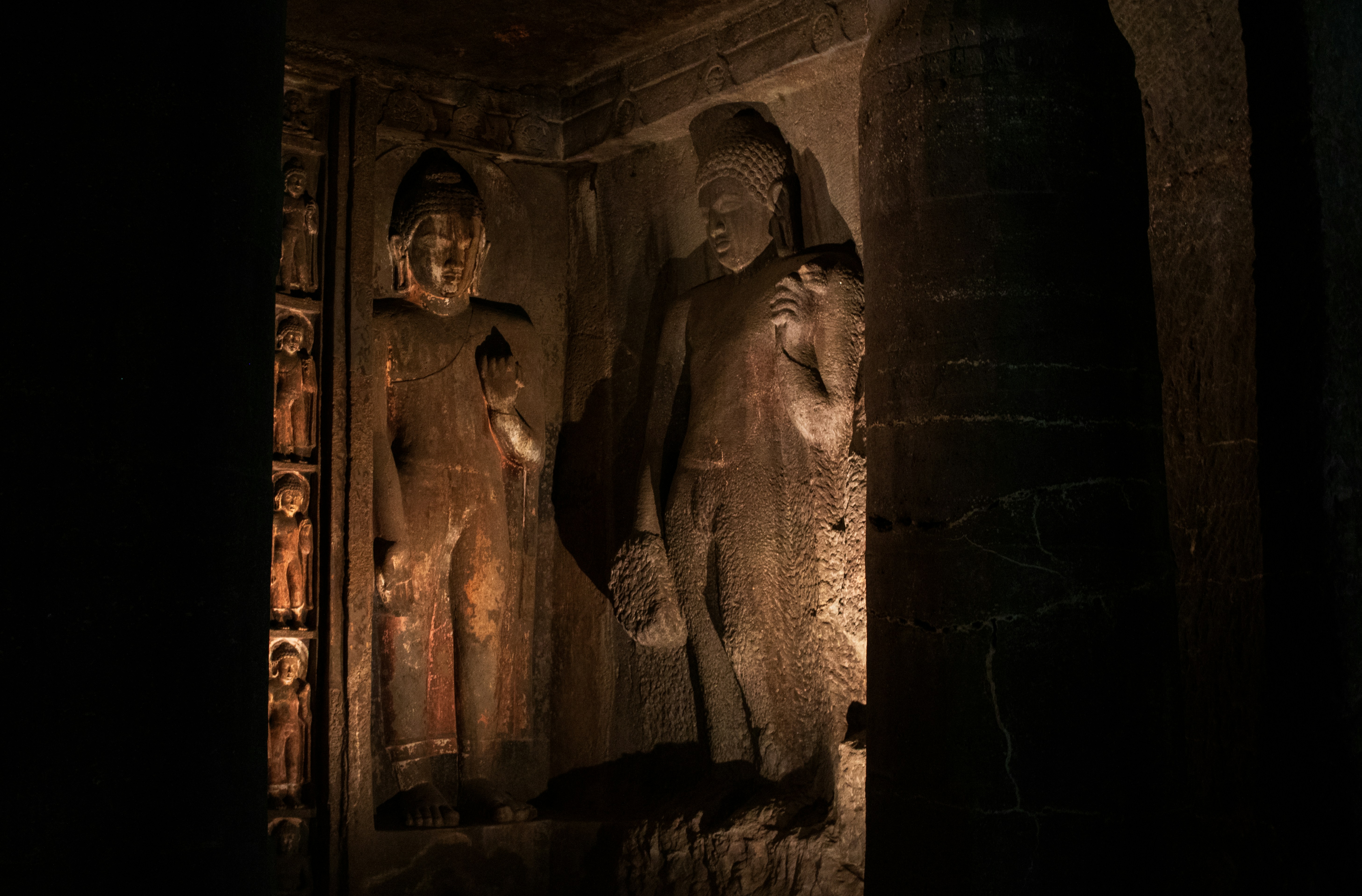Sculpted standing Buddha figures carved into the rock walls of the Ajanta Caves in Maharashtra, India