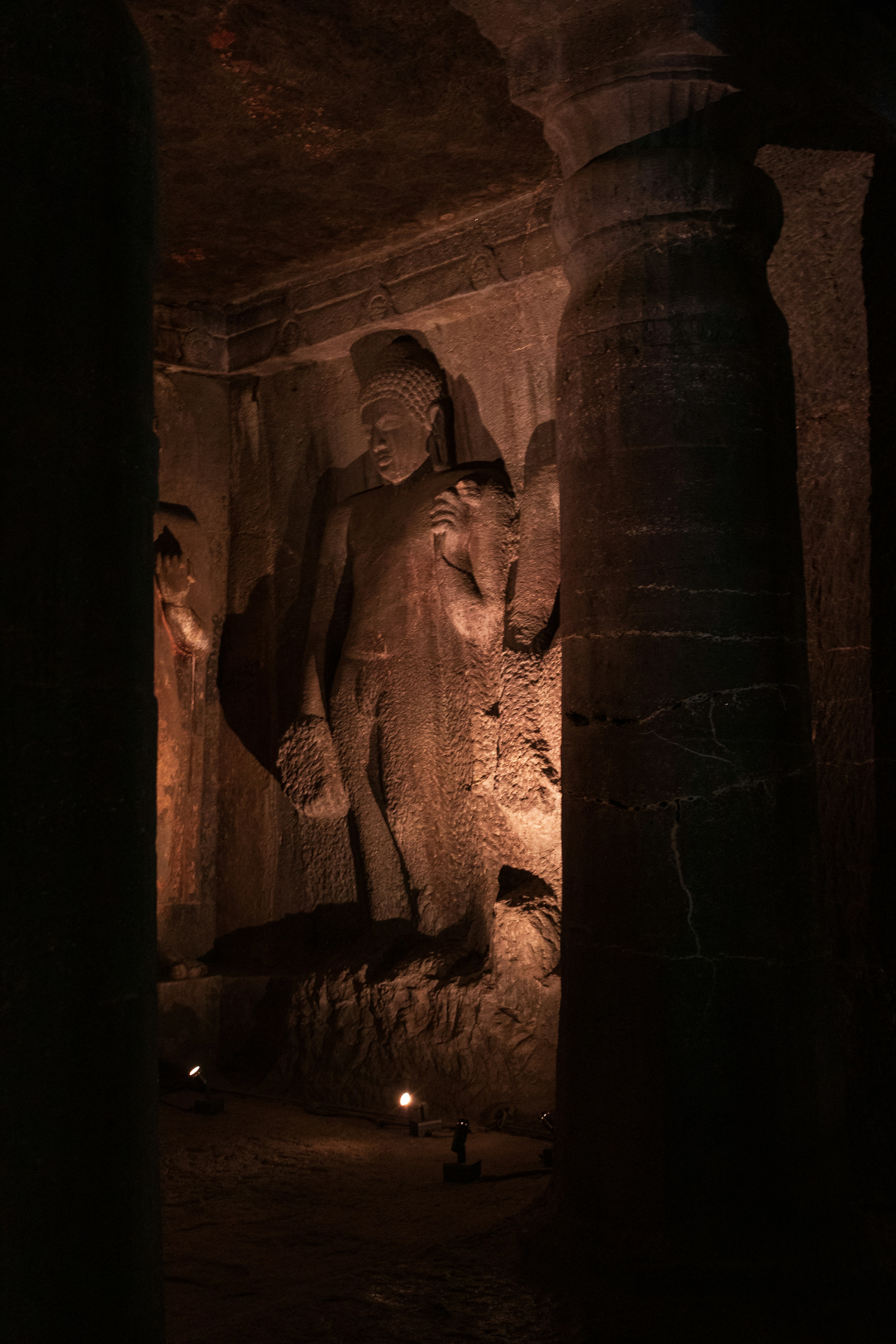 A standing Buddha figure carved into the rock wall of the Ajanta Caves in Maharashtra, India