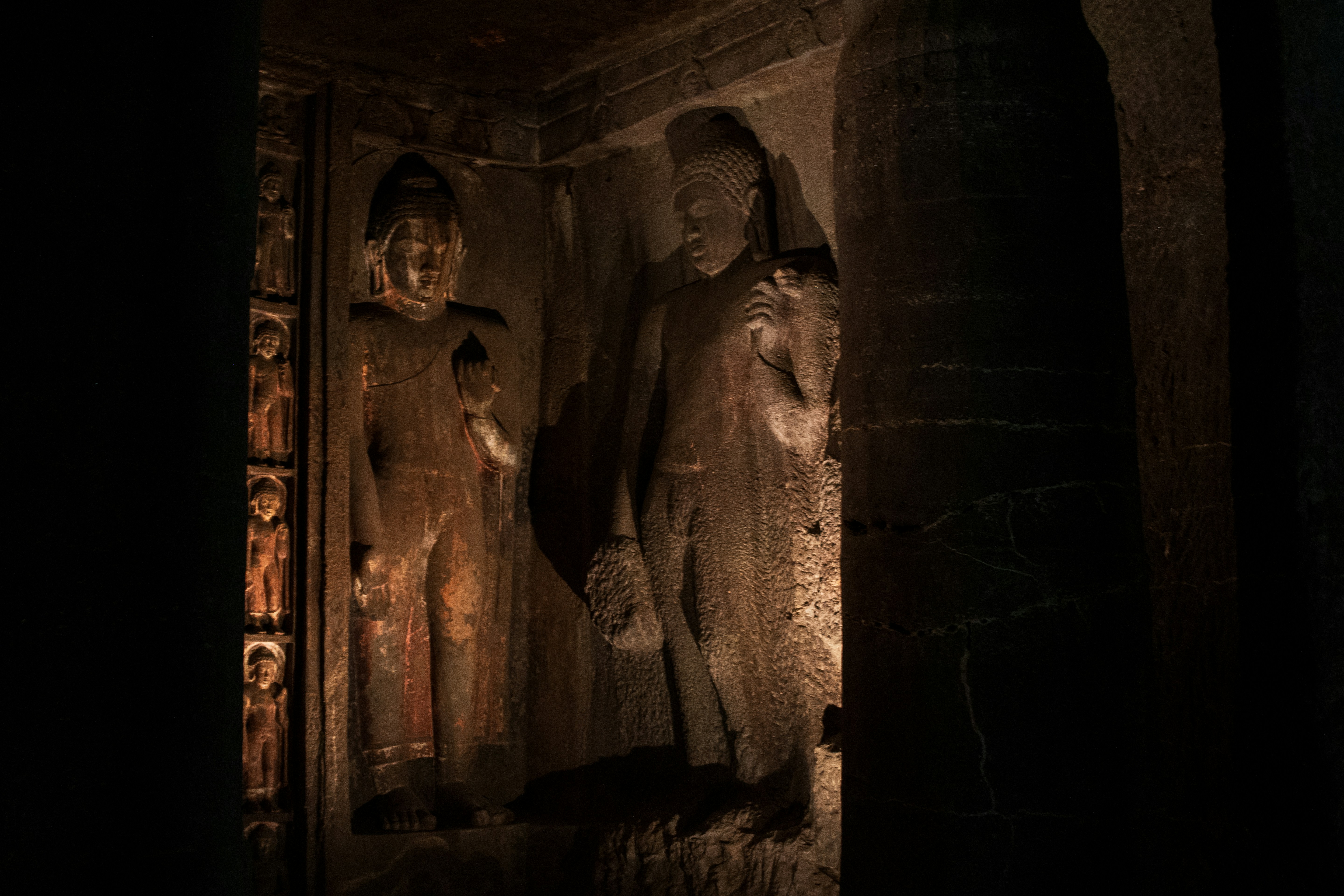 Standing Buddha figures carved into the rock walls of the Ajanta Caves in Maharashtra, India