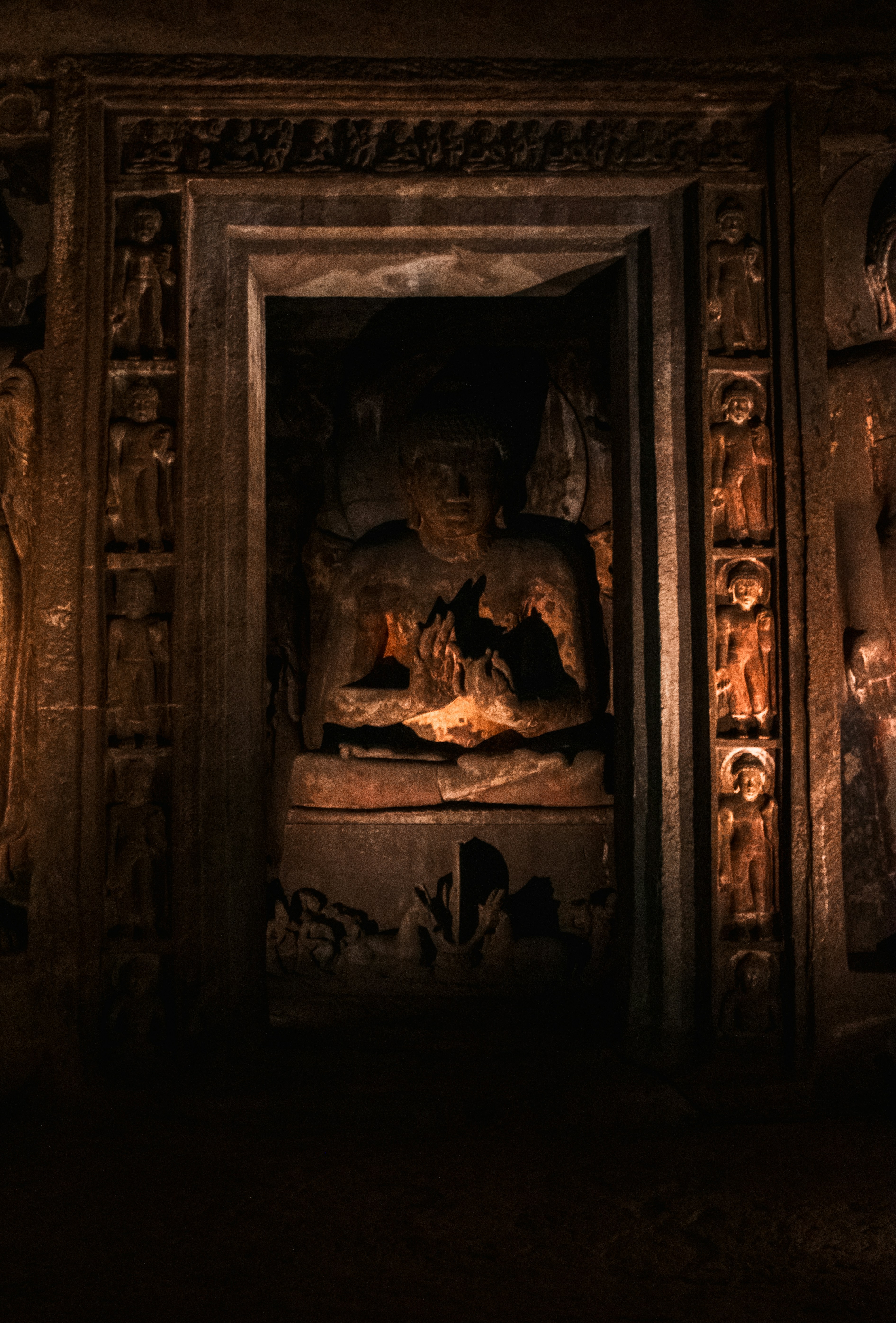 A seated Buddha statue carved into a stone wall at the Ajanta Caves in India