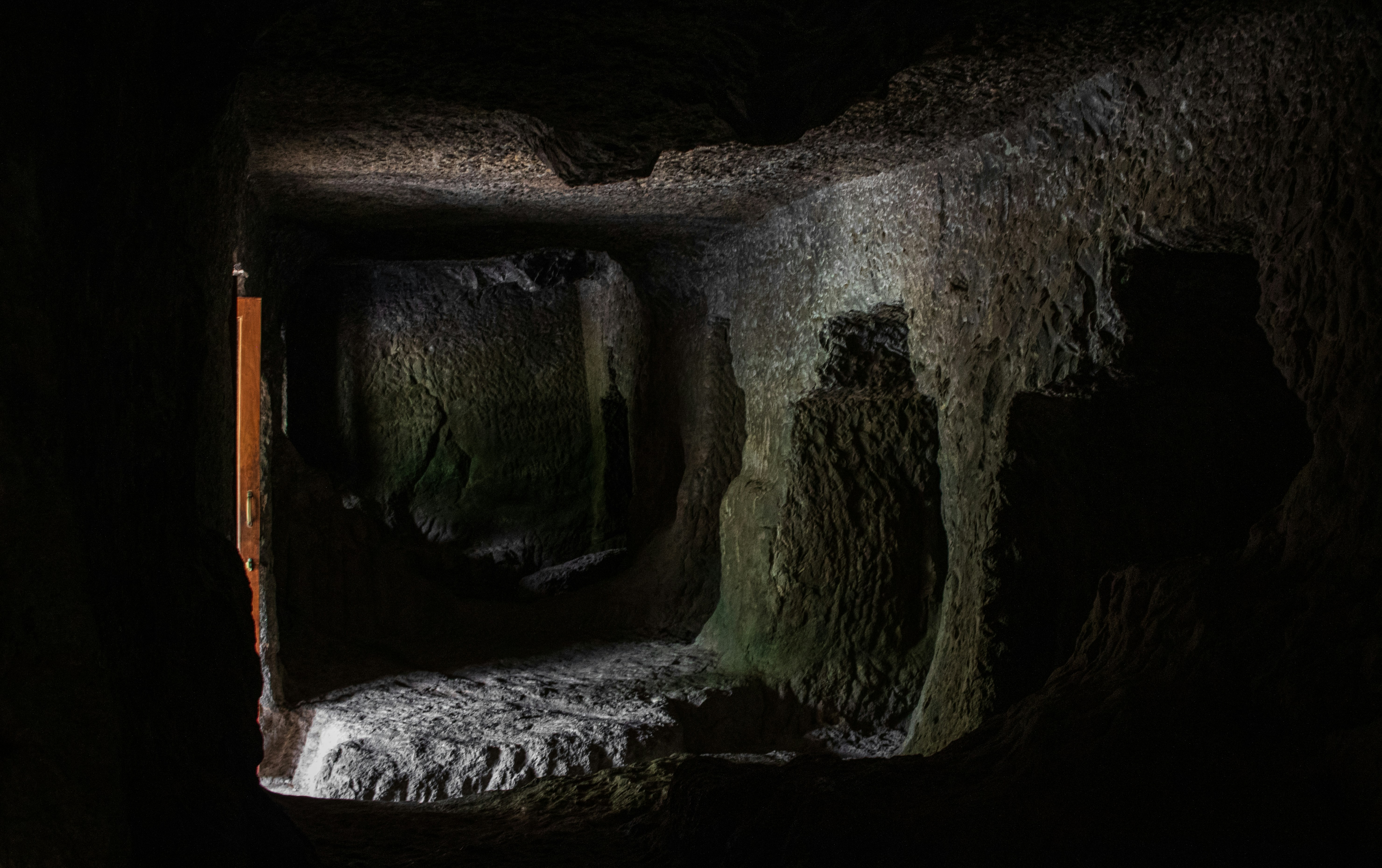 A dimly lit interior of an unfinished rock-cut cave at the Ajanta Caves in India