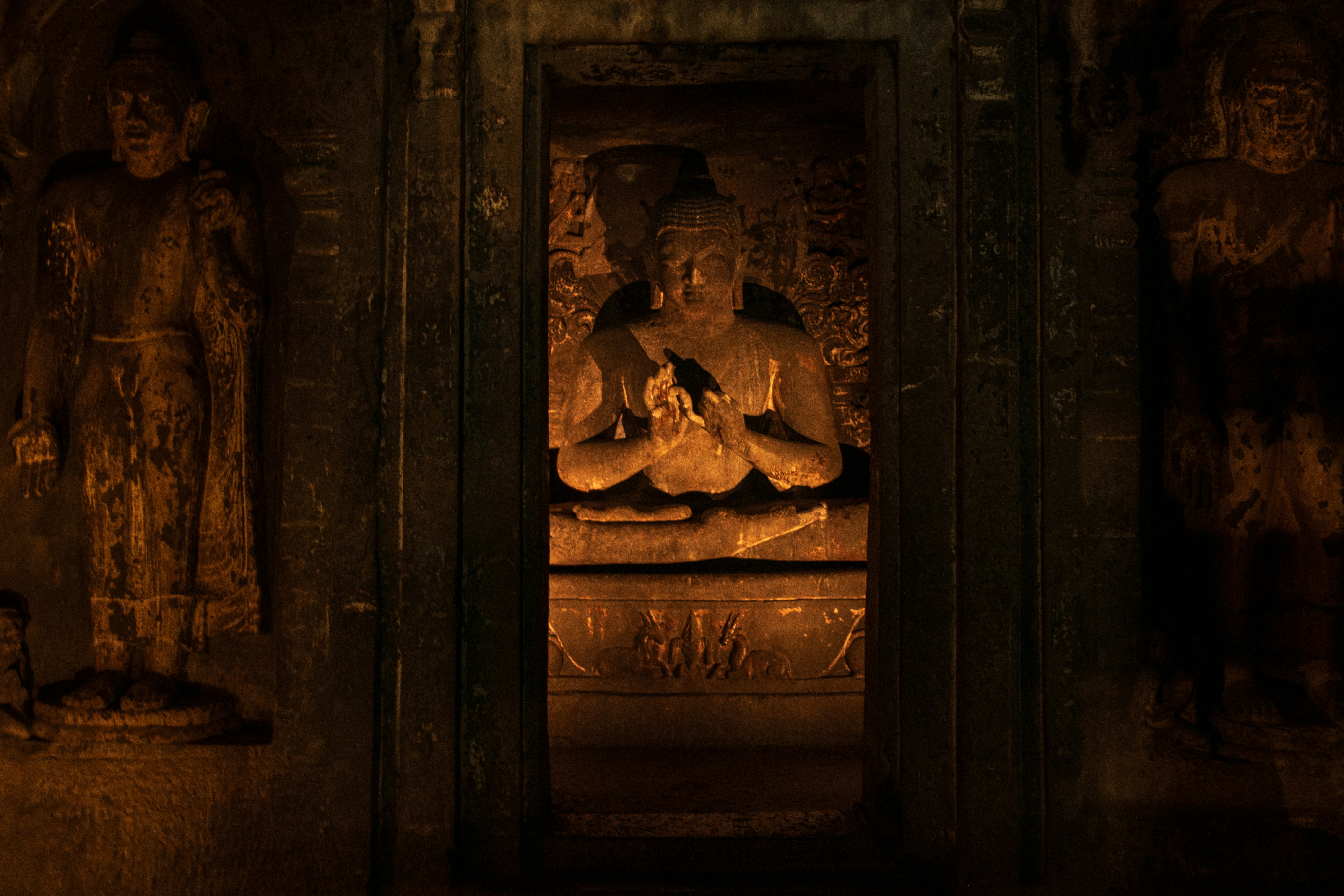 A seated Buddha statue in a dimly lit rock-cut shrine at the Ajanta Caves in Maharashtra