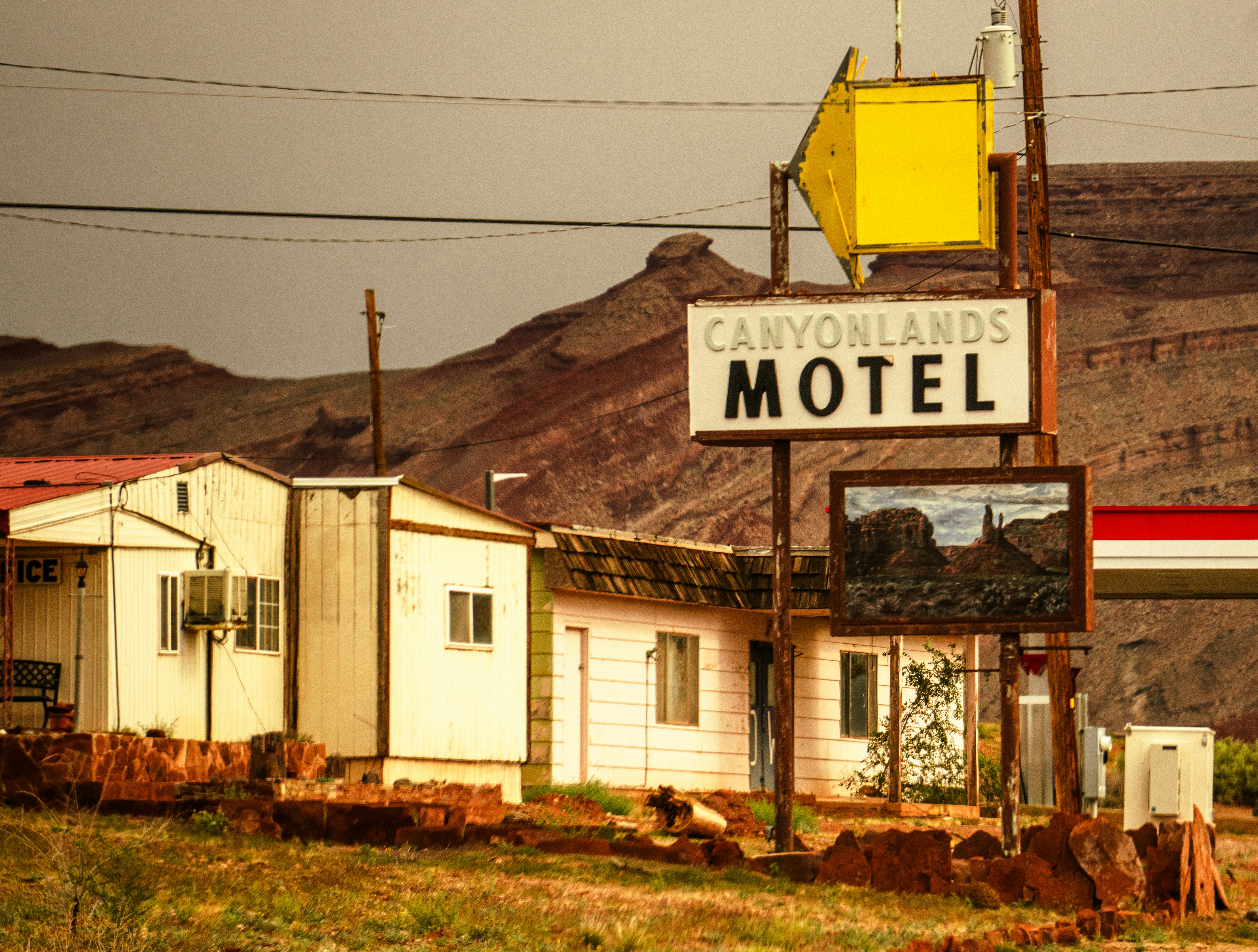 Un cartello con la scritta Canyonlands Motel davanti a un edificio bianco e montagne di roccia rossa