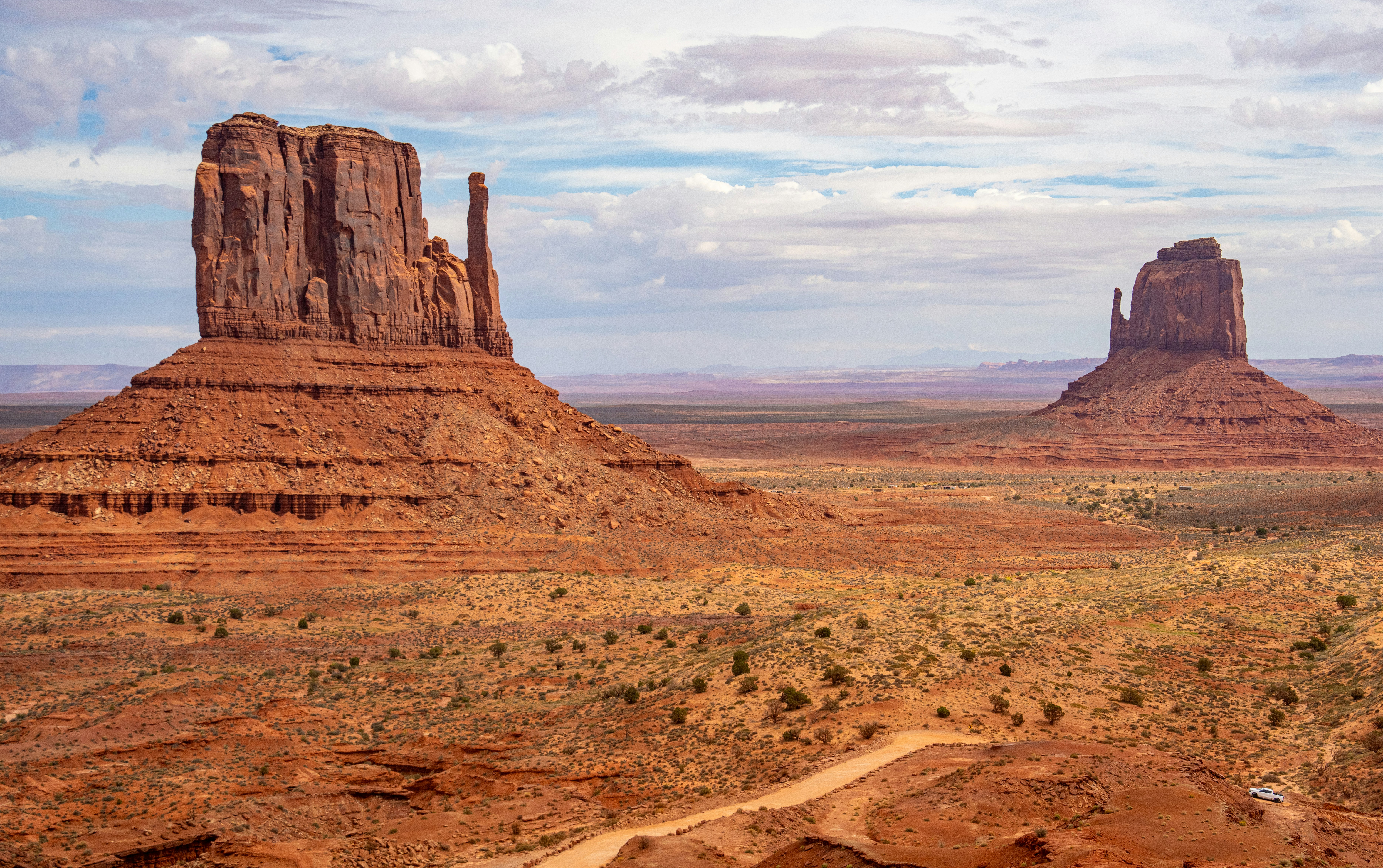 Butte di arenaria rossa che si innalzano sopra il suolo desertico nella Monument Valley sotto un cielo nuvoloso