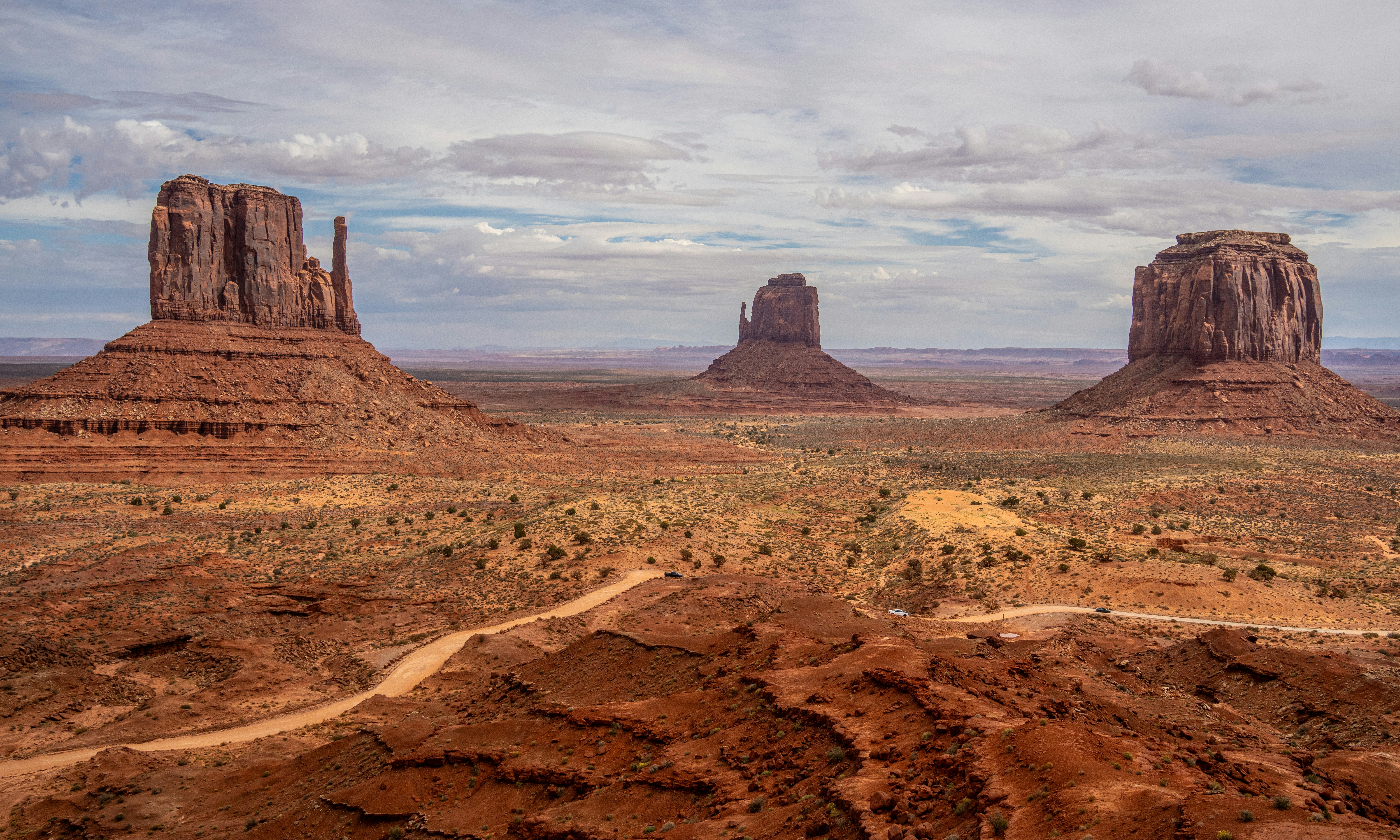 Butte di arenaria rossa che si ergono dal suolo desertico nella Monument Valley sotto un cielo nuvoloso