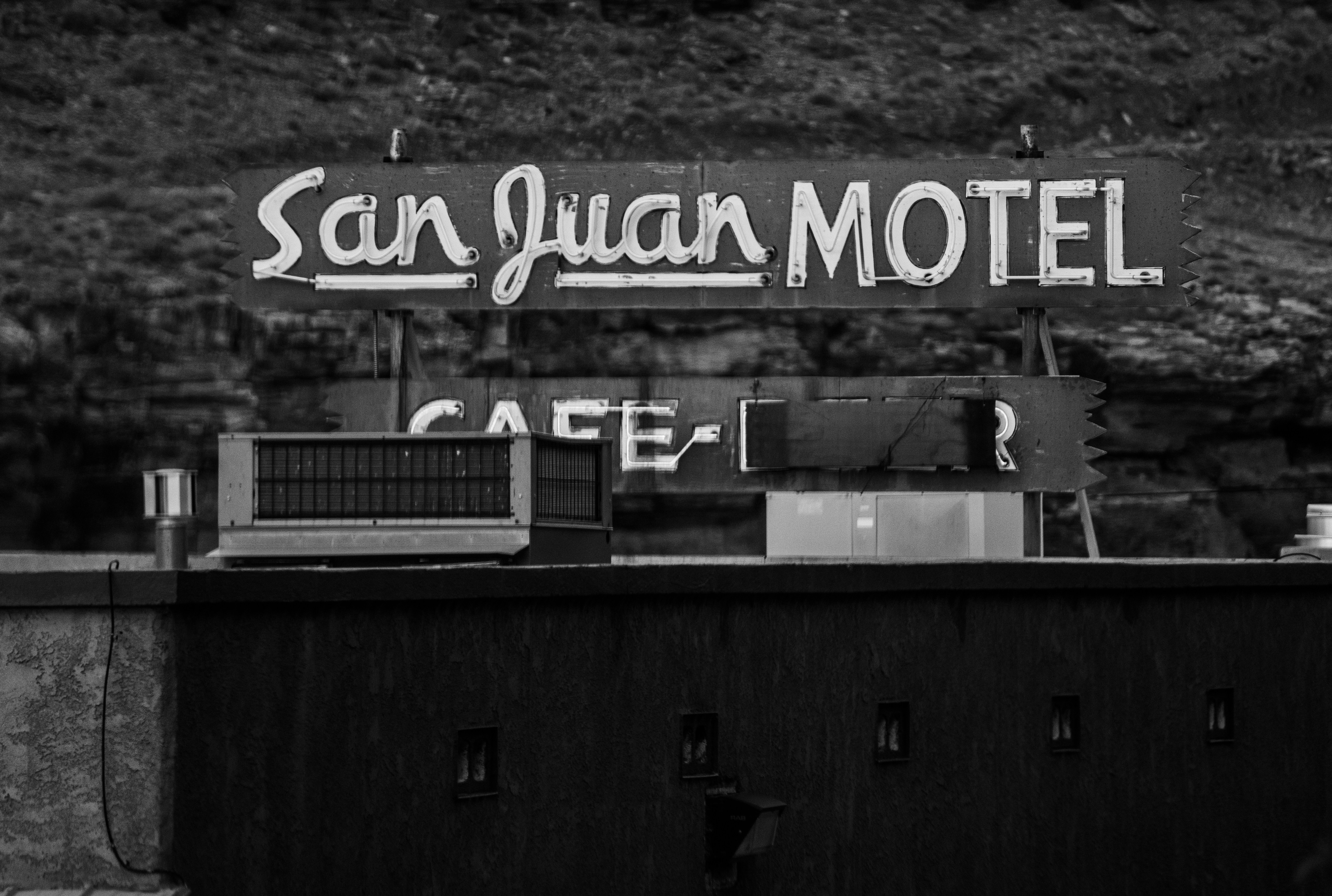 Un cartello bianco e nero con la scritta San Juan MOTEL sopra il tetto di un edificio buio