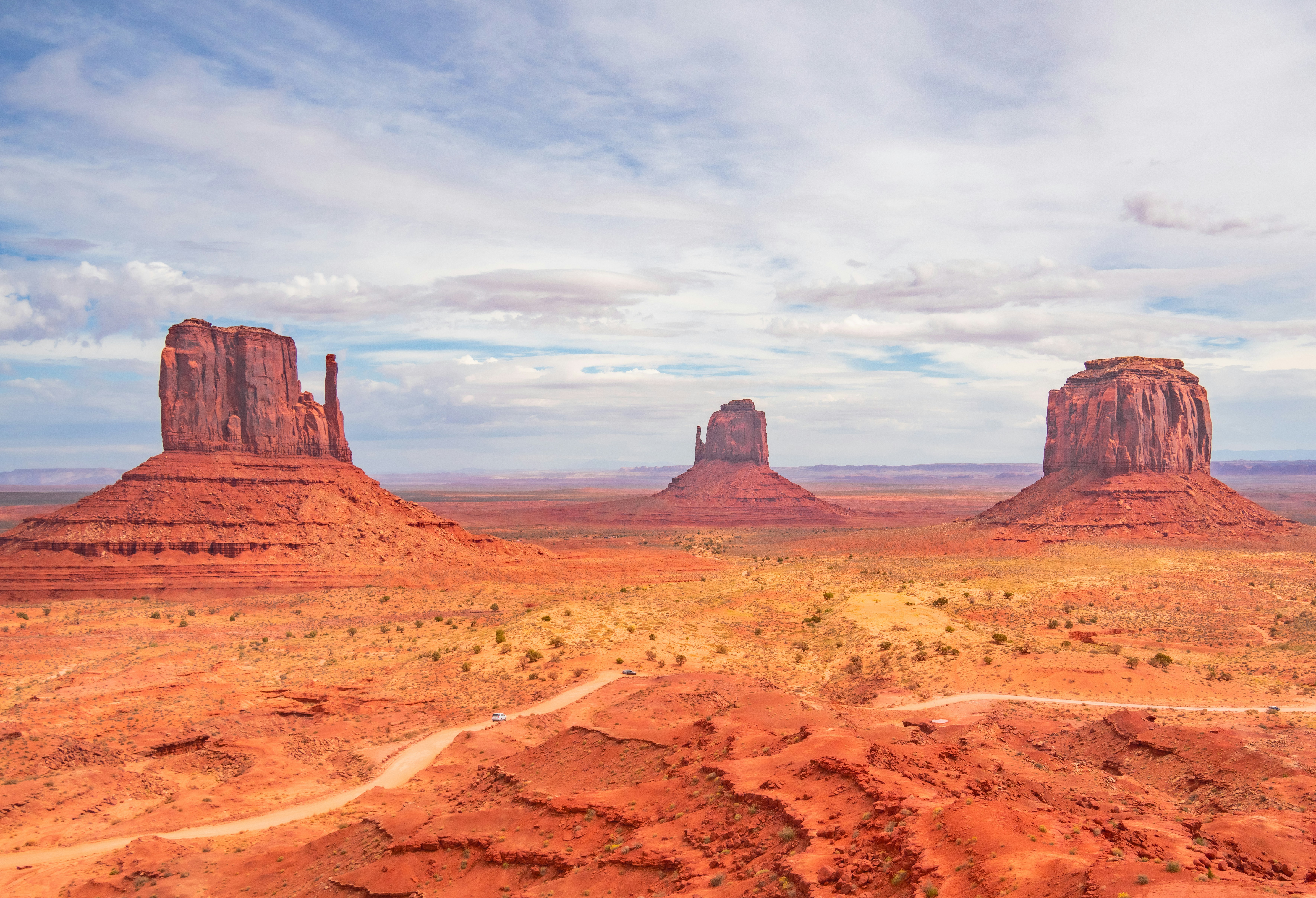 Butte di arenaria rossa che si ergono dal suolo desertico nella Monument Valley sotto un cielo nuvoloso