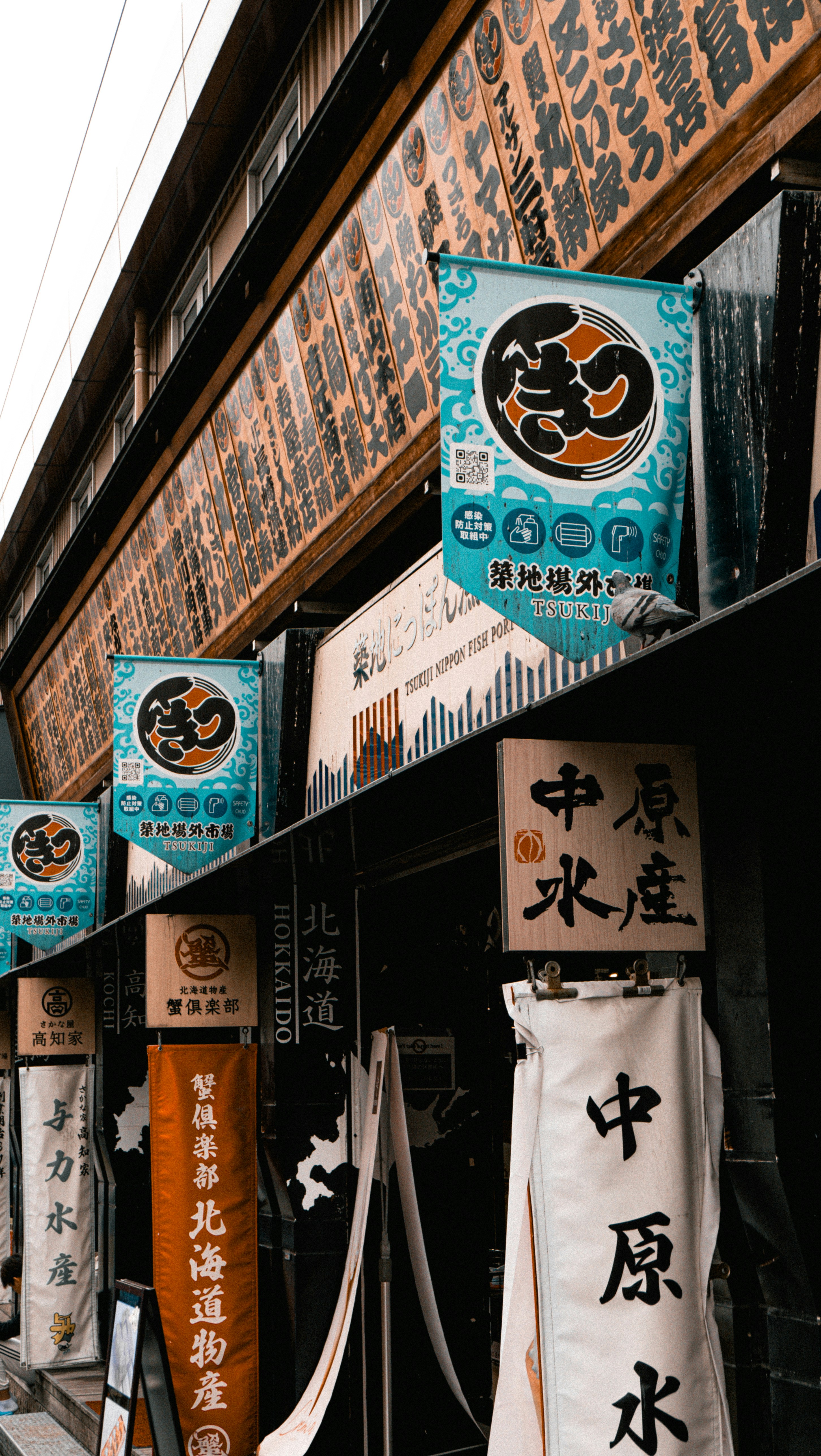 Traditional Japanese banners and wooden signs hanging outside a fish market in Tsukiji, Tokyo