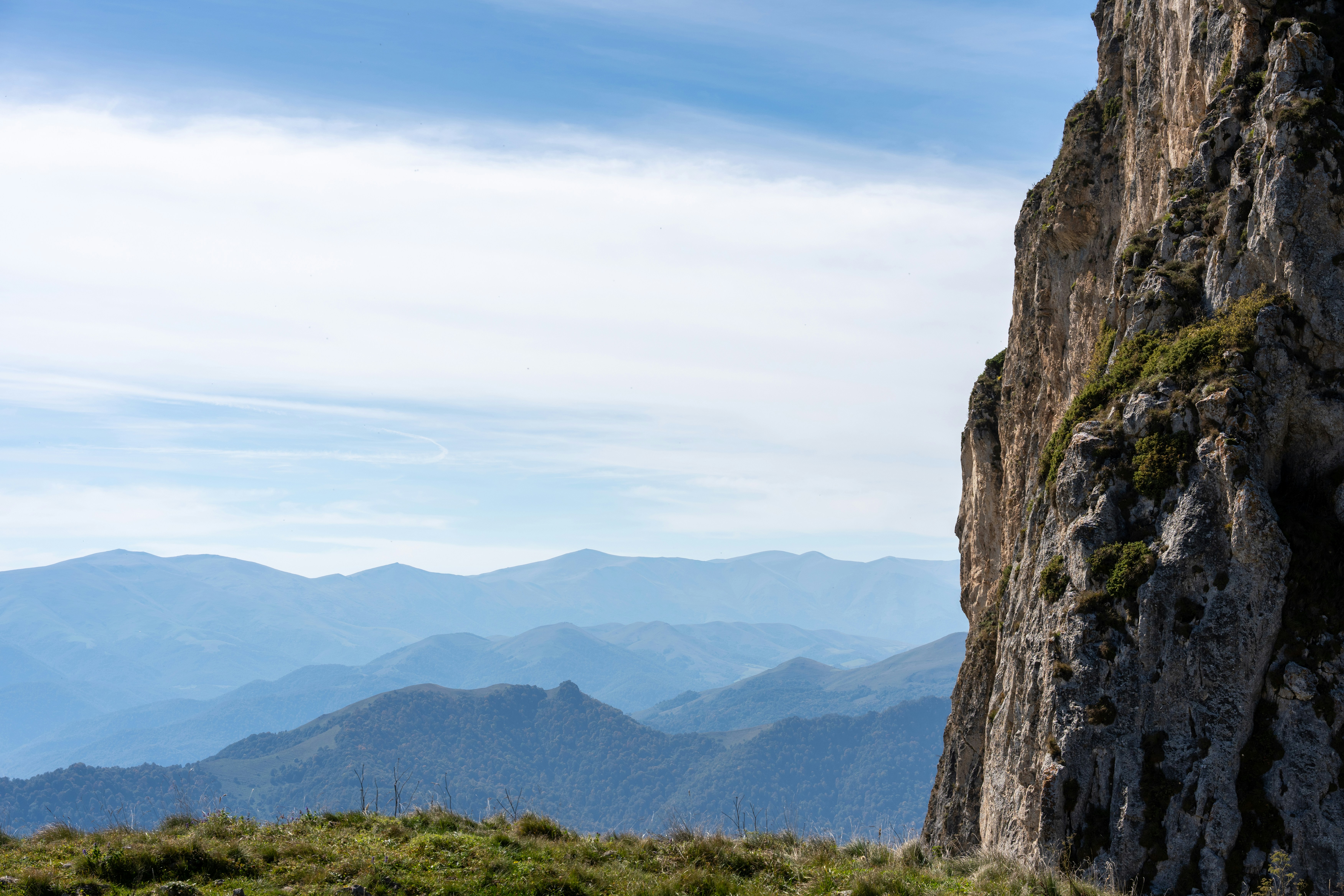 Rocky cliff overlooking blue mountain range - Free Photo on Unsplash