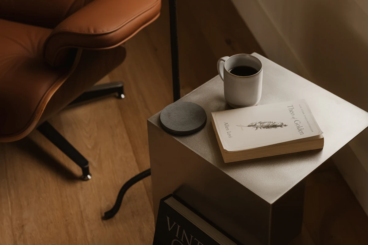 Book and mug on a small side table beside a reading chair