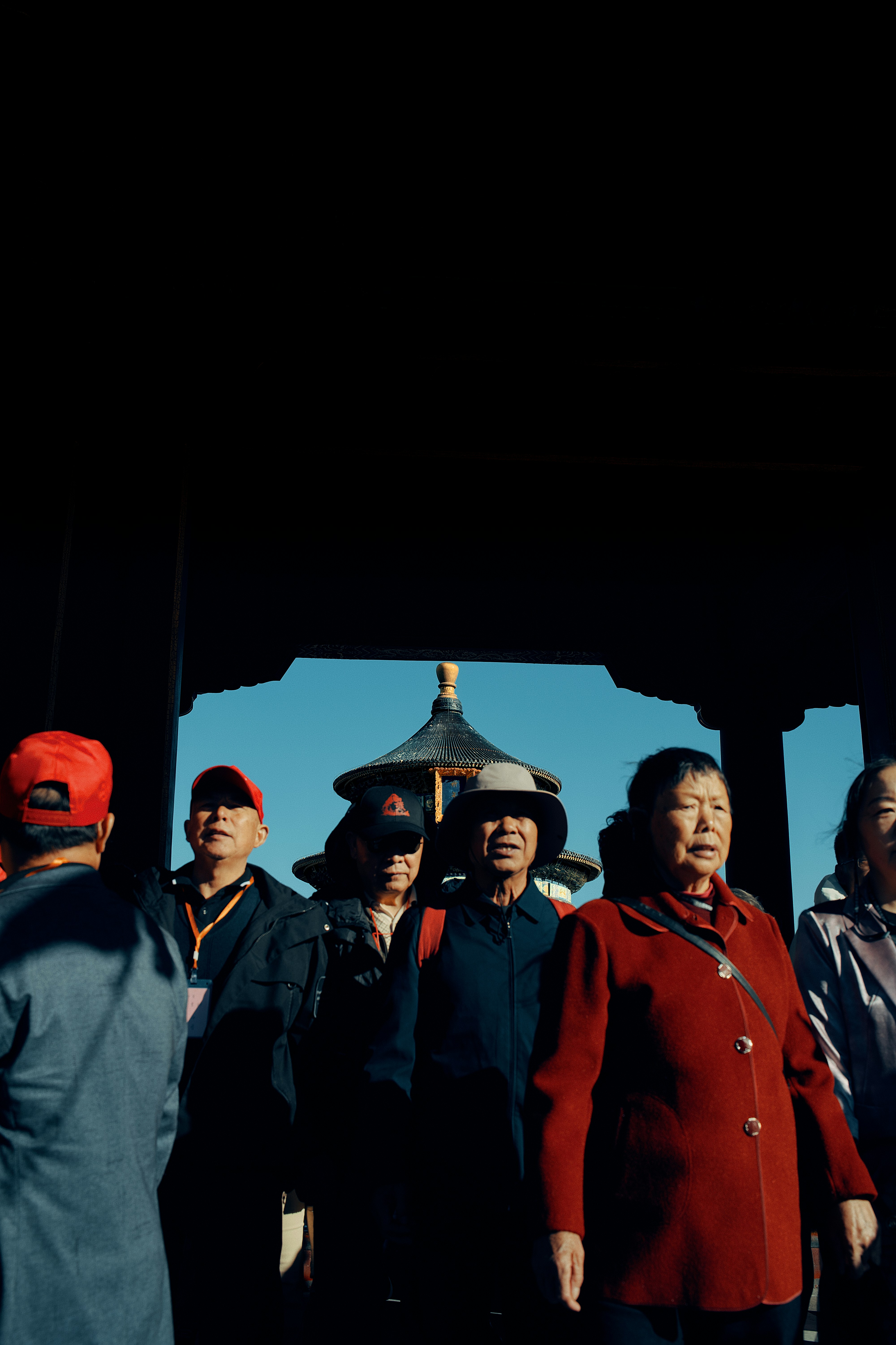 A group of adults walking through a dark archway toward the Temple of Heaven in Beijing