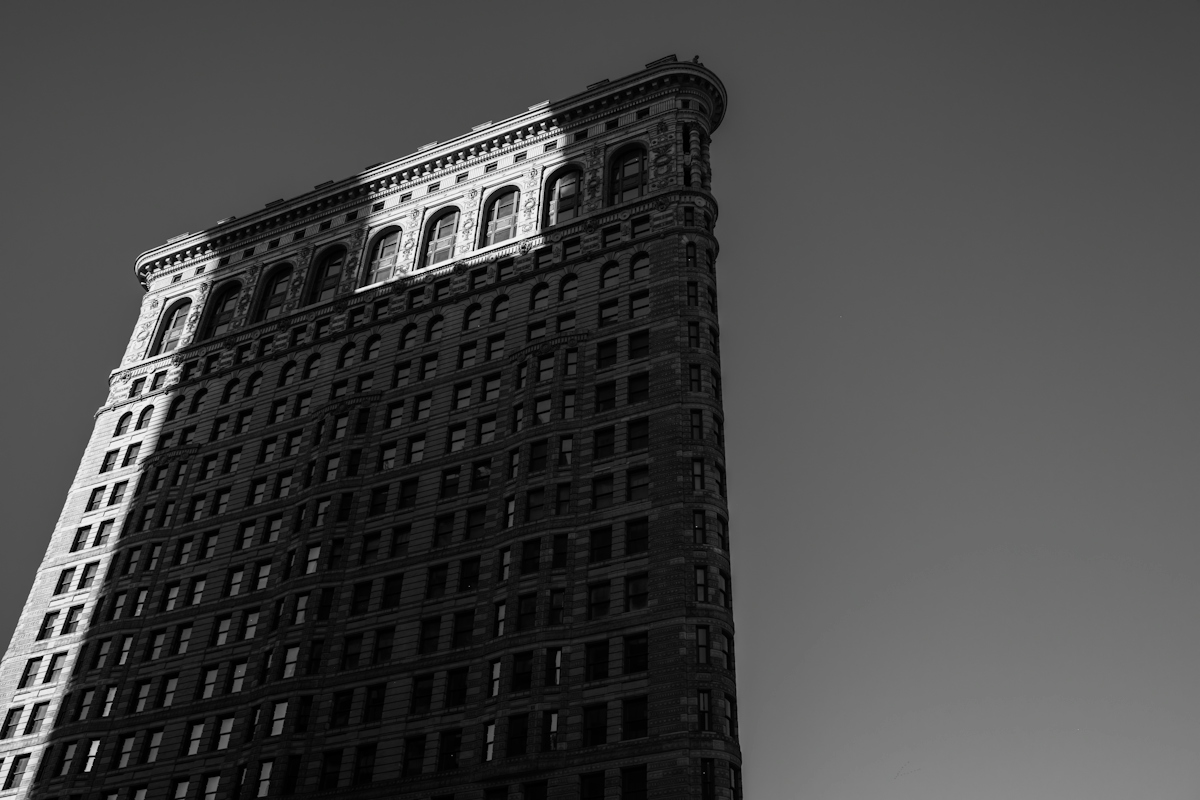 The Flatiron Building in New York City under bright sunlight with deep shadows