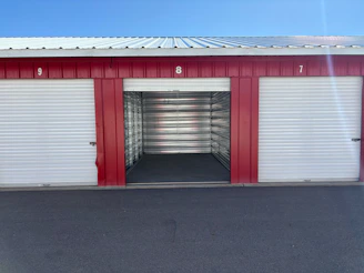 An open storage unit door numbered eight between two closed units under a metal roof