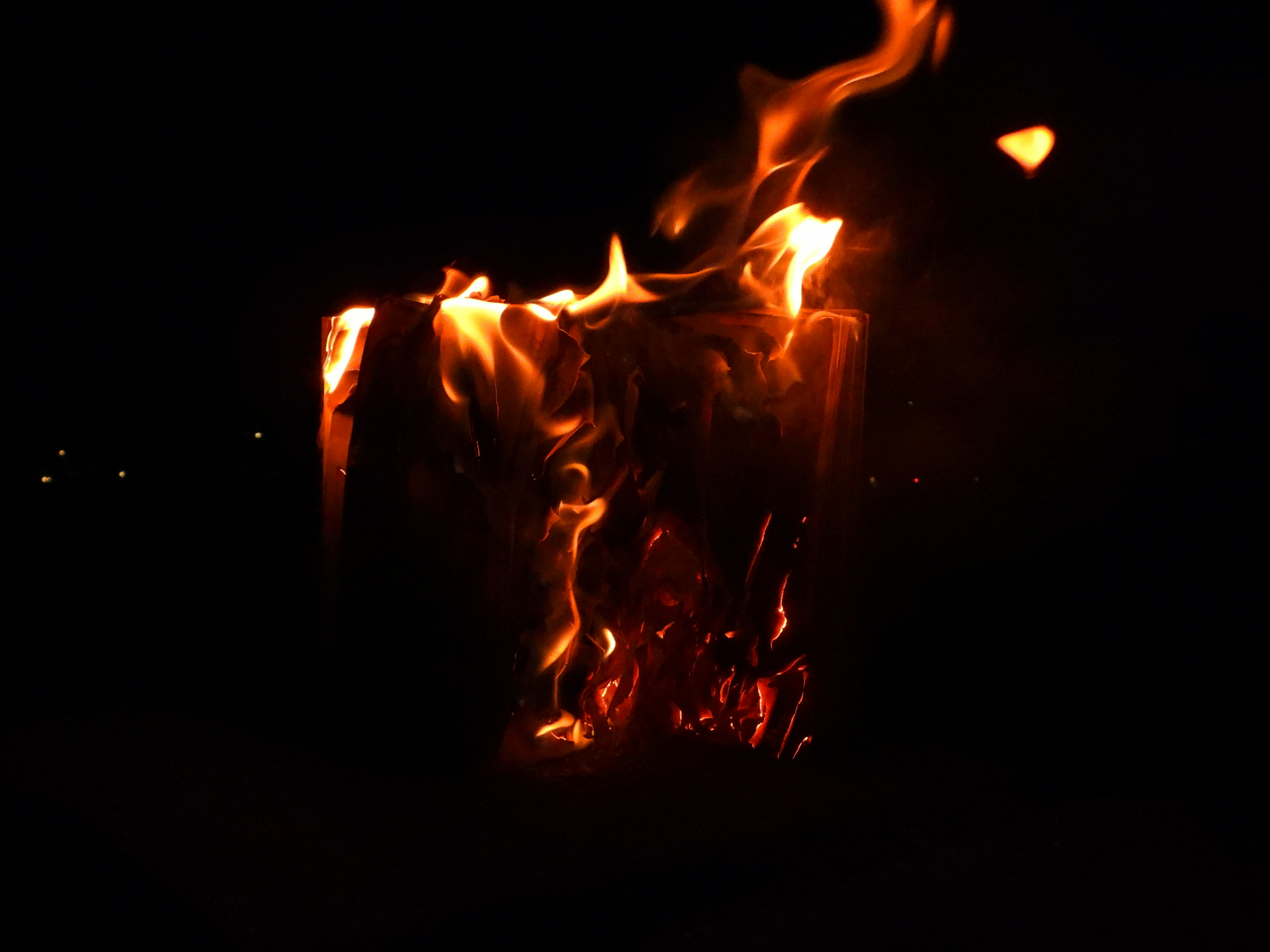 Bright orange flames engulfing a book against a dark background