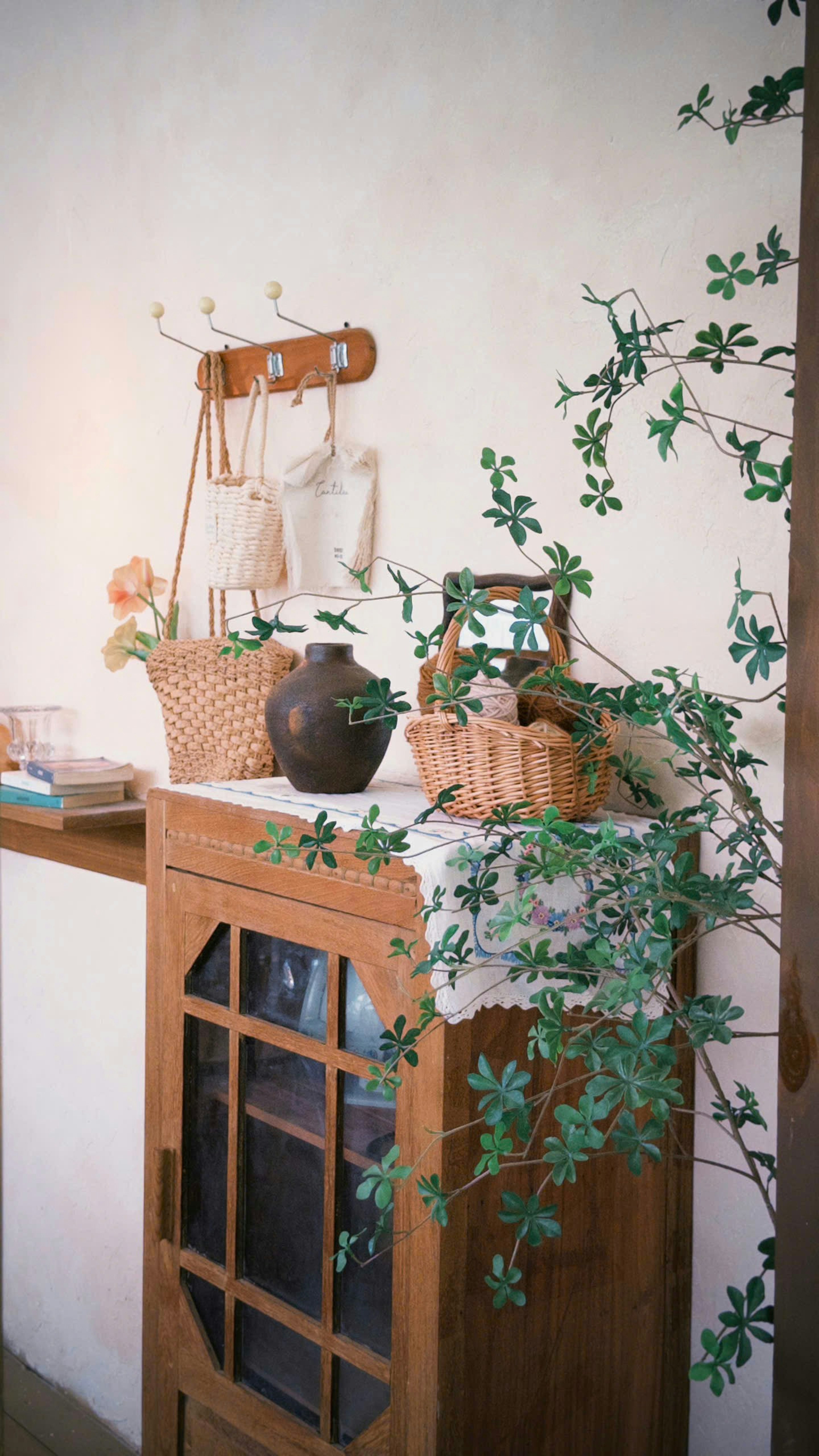 A wooden cabinet with a dark vase and a wicker basket on a lace runner