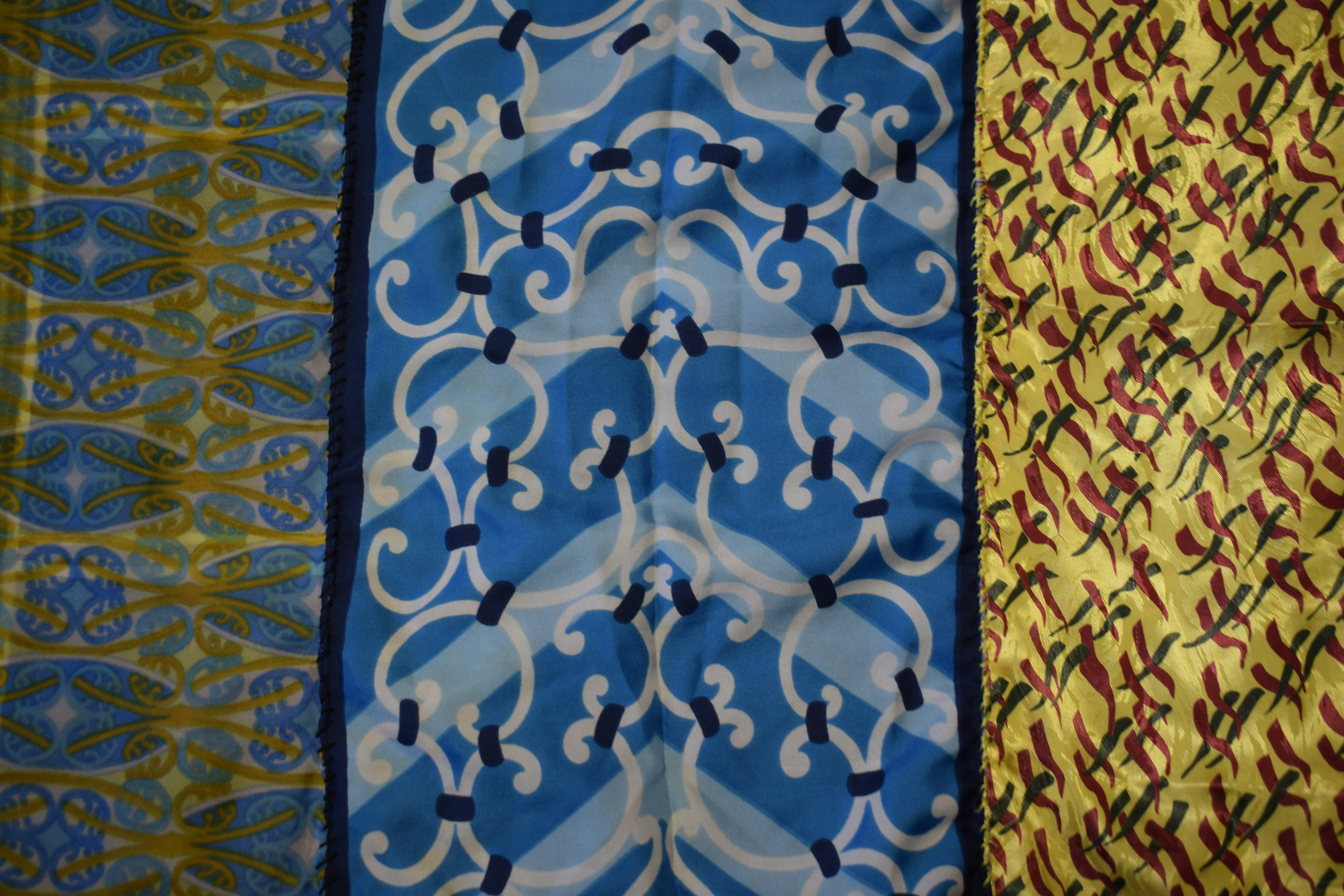 Three vertical panels of patterned fabric in blue, yellow, and white