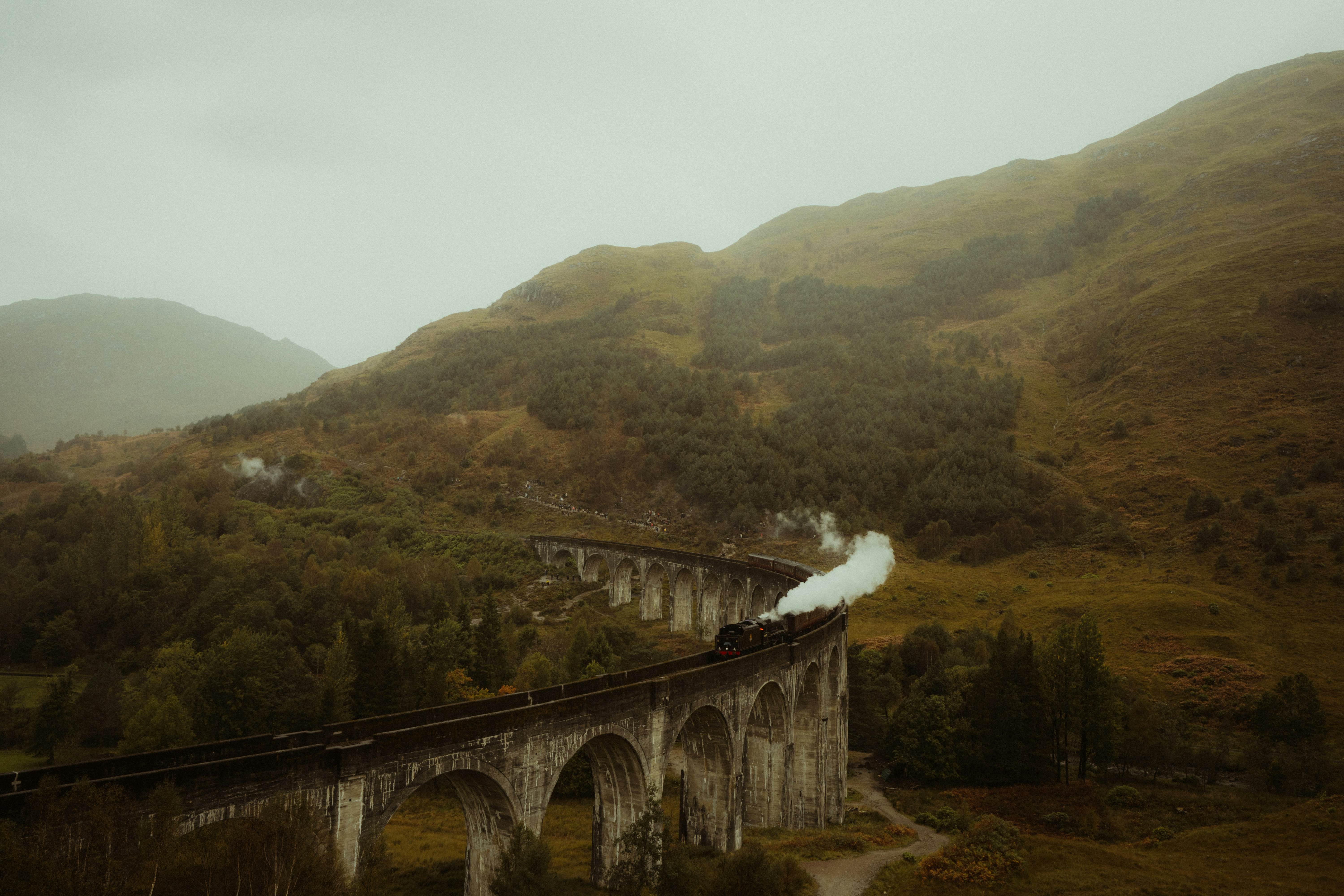 A steam train crossing the Glenfinnan Viaduct in the misty Scottish Highlands