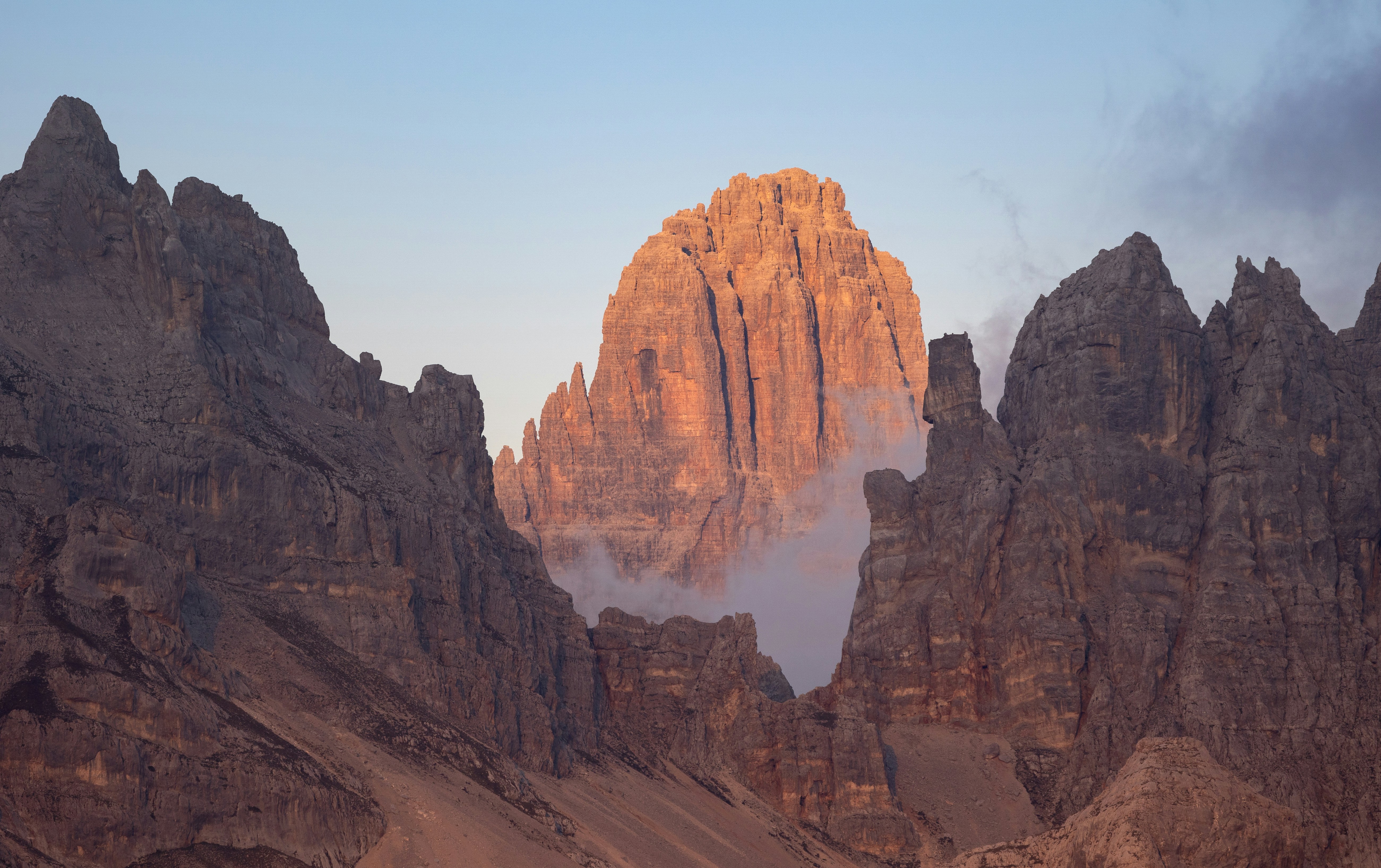 A jagged mountain peak glowing in warm golden light above a layer of low clouds