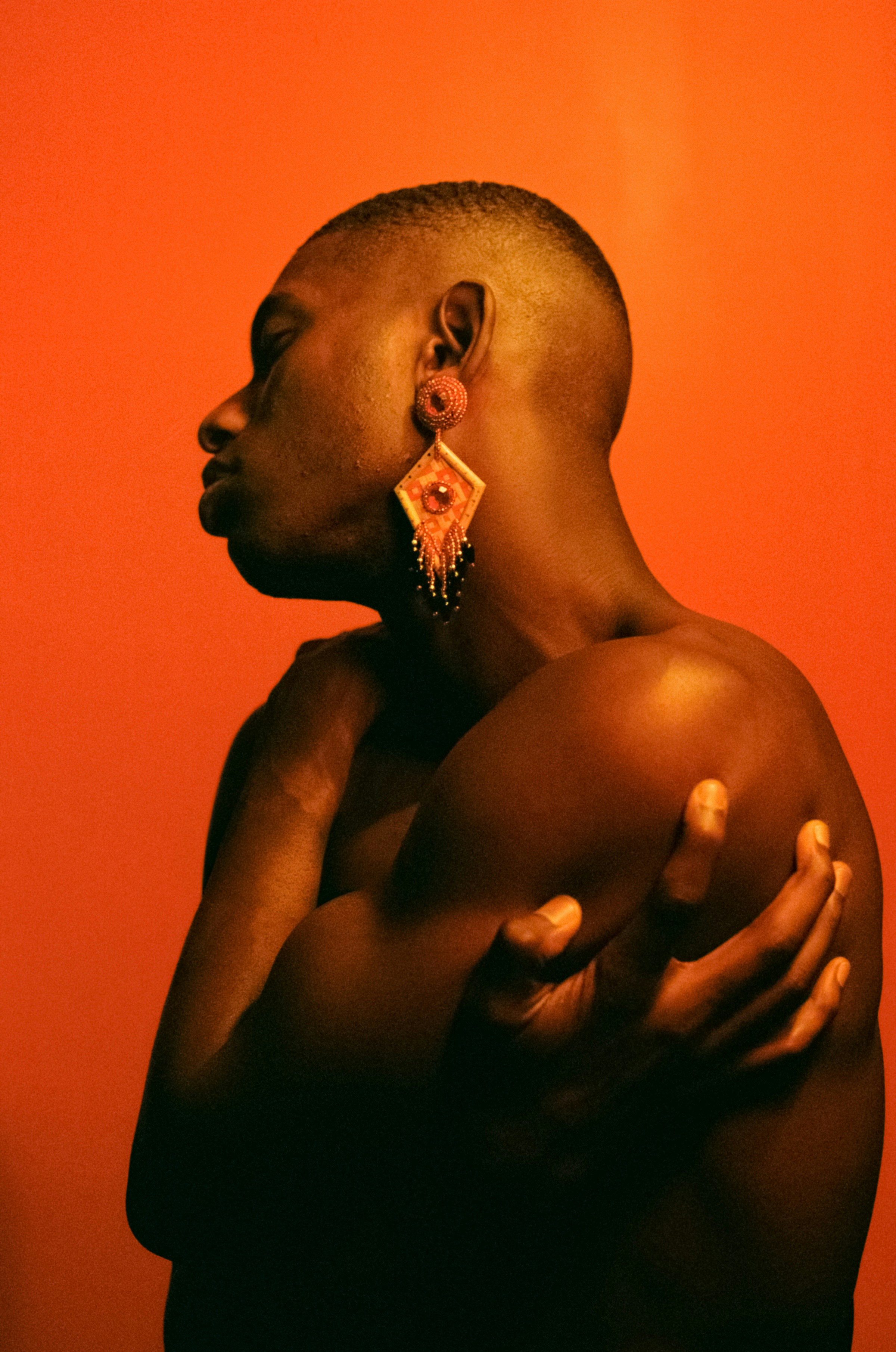 In profile, arms crossed, beaded earring catching the light