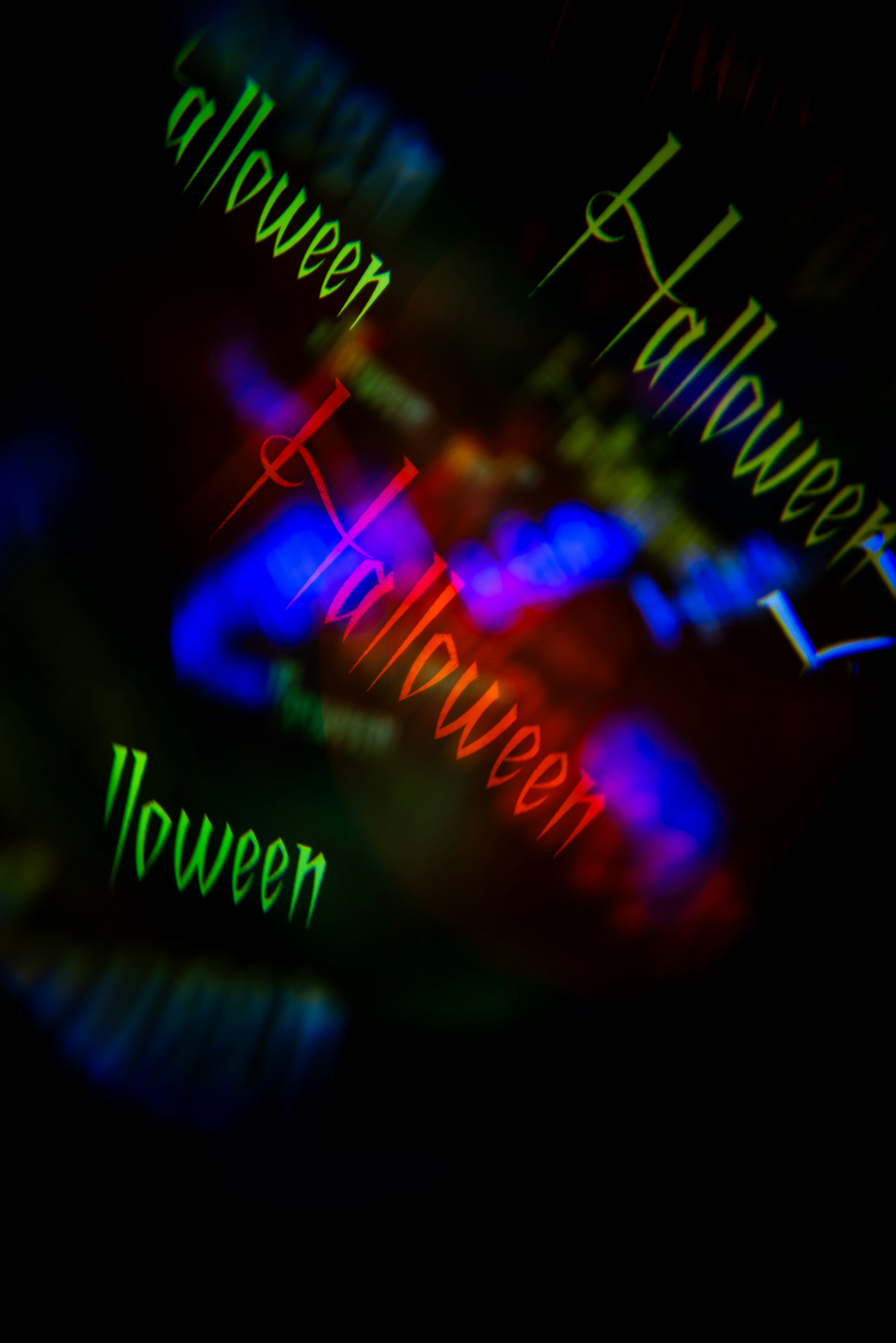 Le mot Halloween répété en texte coloré et lumineux sur un fond sombre