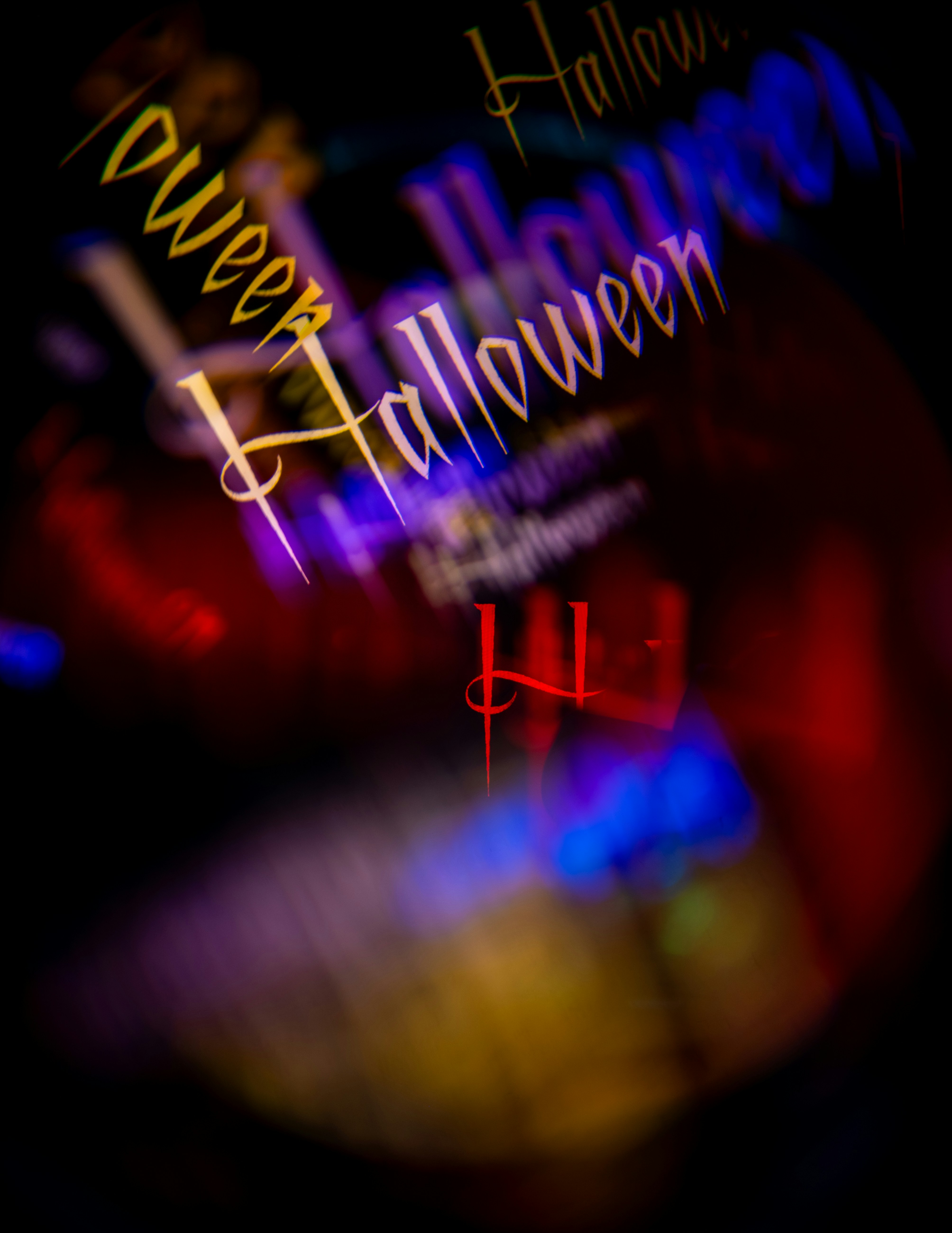 Le mot Halloween répété en écriture stylisée avec flou de mouvement et traînées lumineuses colorées