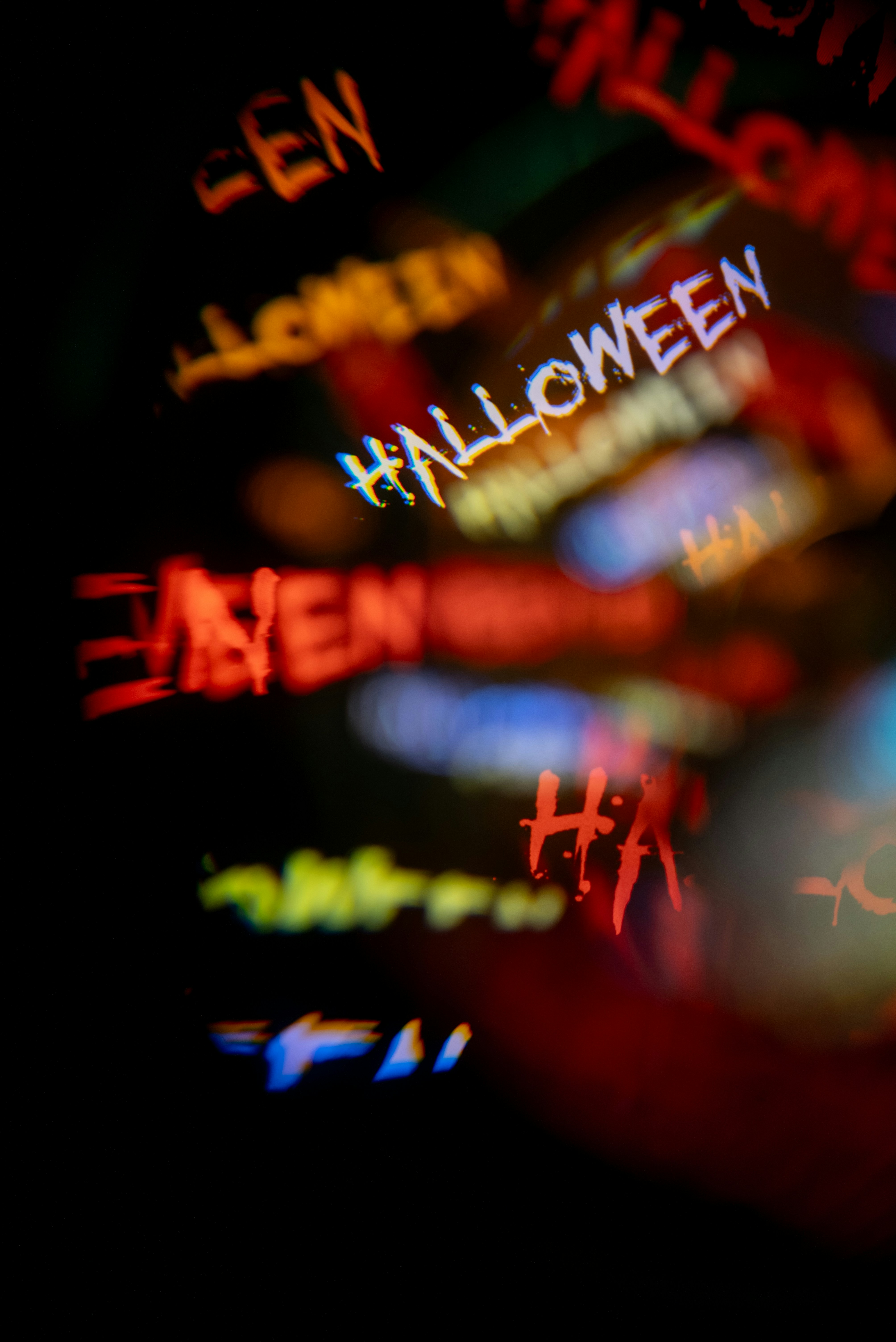 De multiples reflets flous et colorés du mot Halloween sur un fond sombre