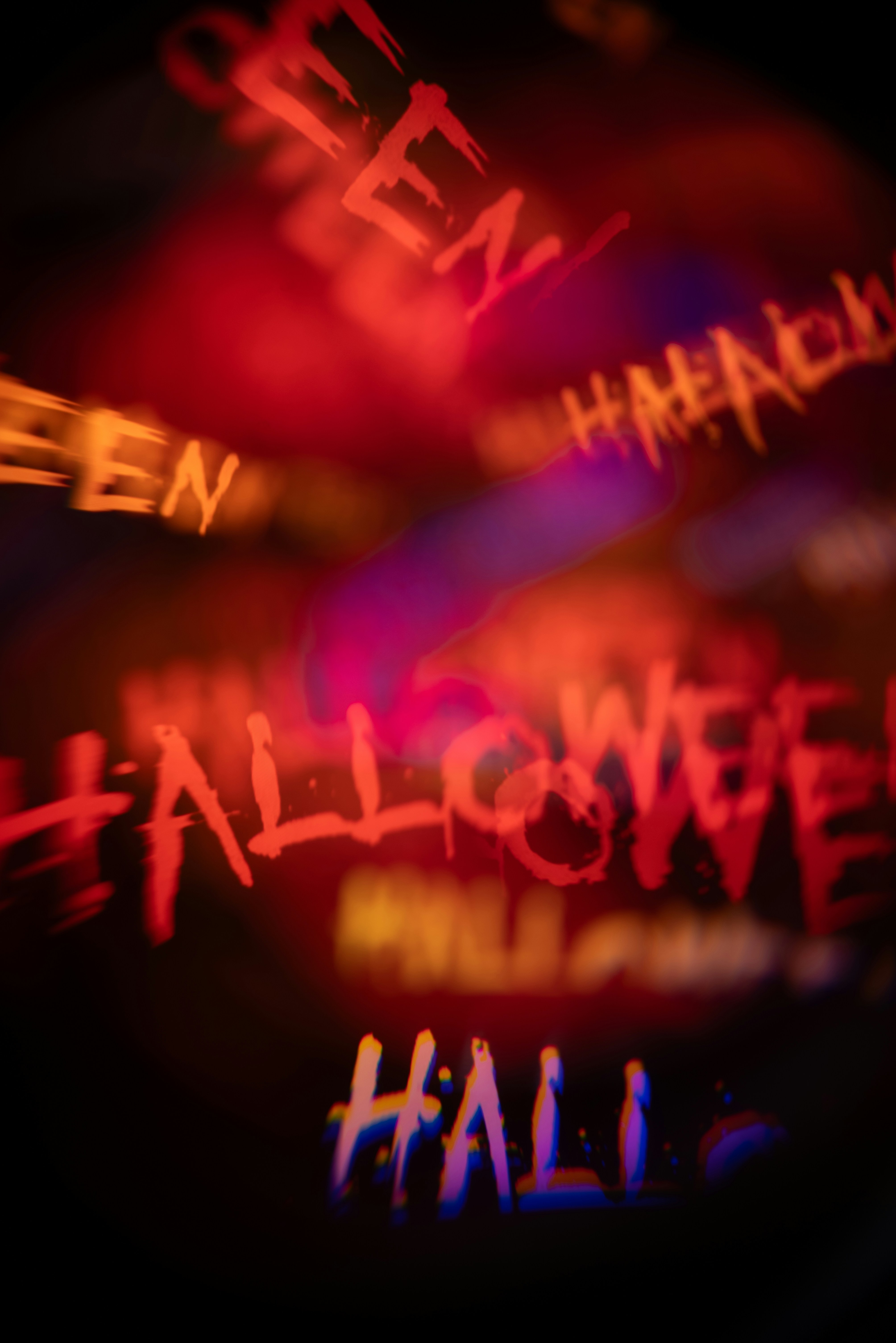 Texte flou rouge et orange disant Halloween sur un fond sombre avec une aberration chromatique