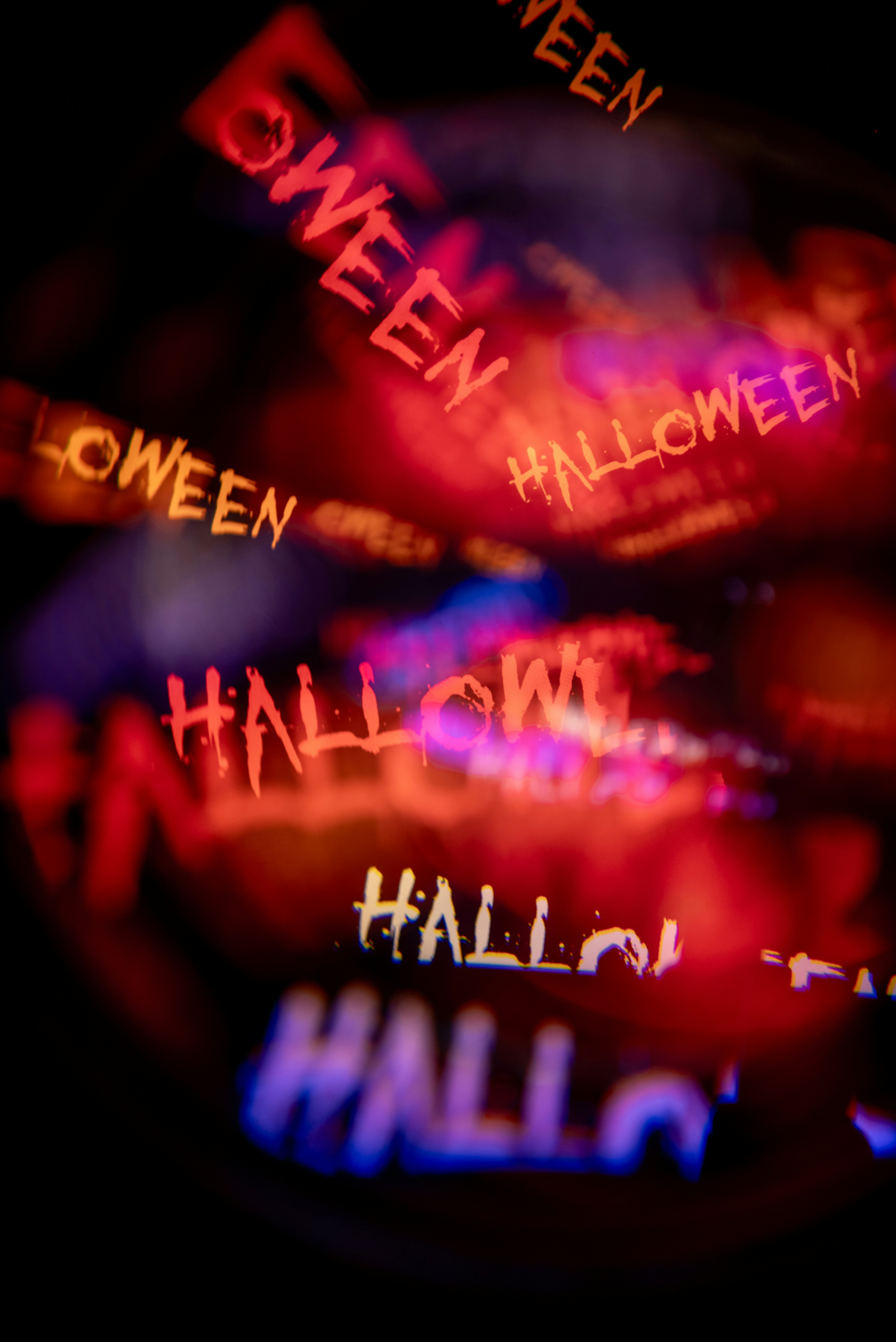 Plusieurs répétitions floues du mot Halloween dans des lumières néon rouges et bleues