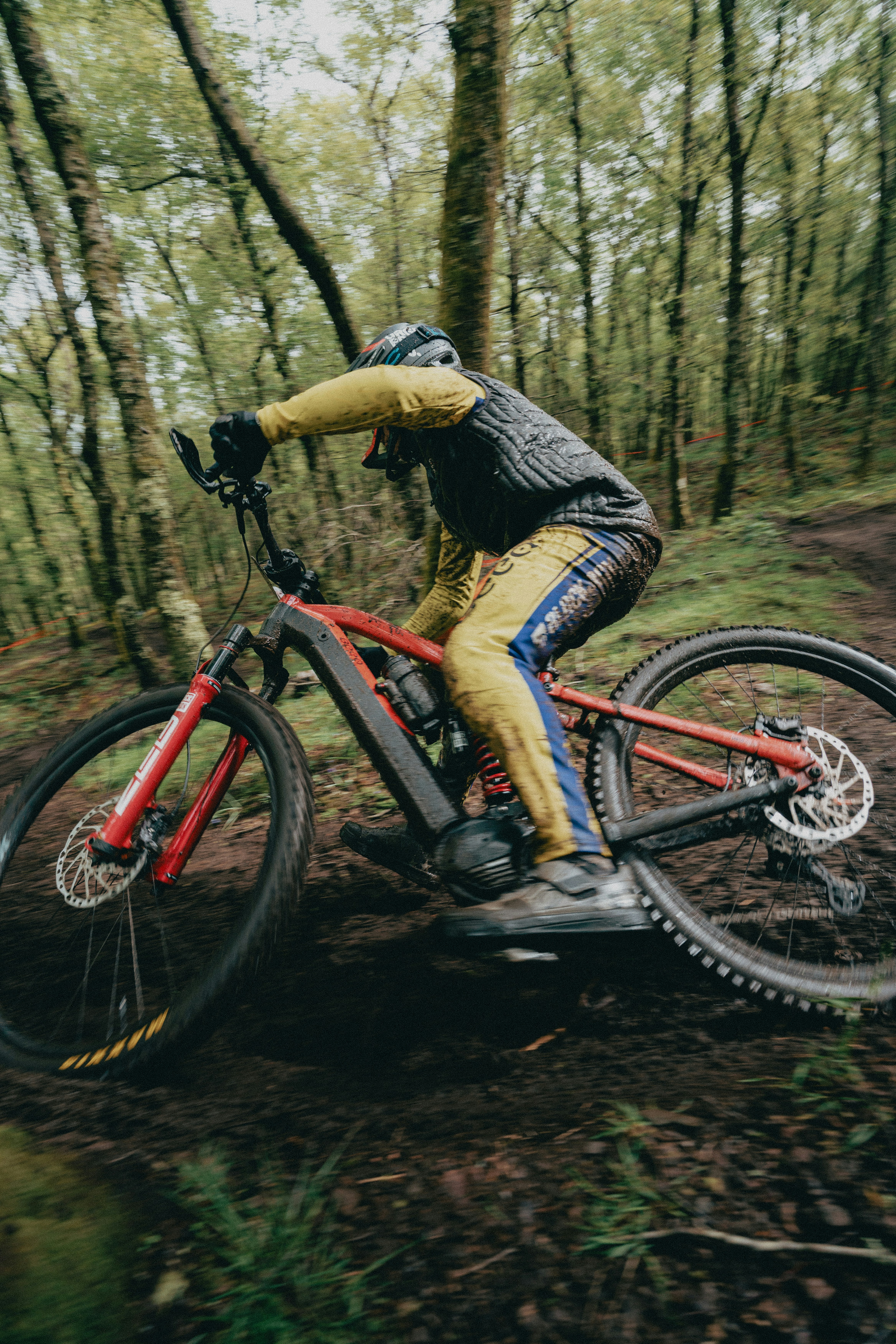 A person mountain biking on a muddy trail through a forest in Lousã, Portugal