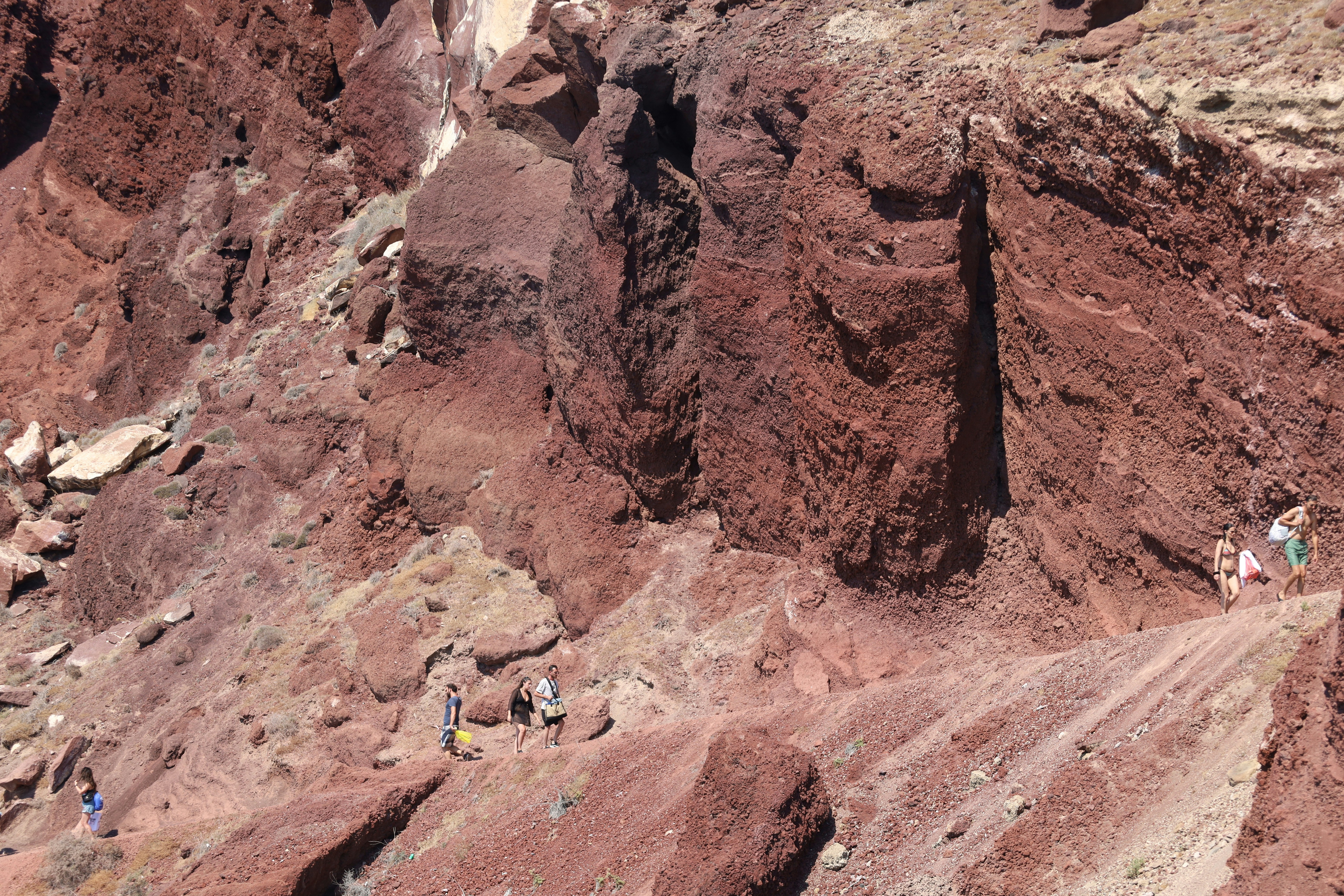 People walking on red volcanic cliff - Free Photo on Unsplash