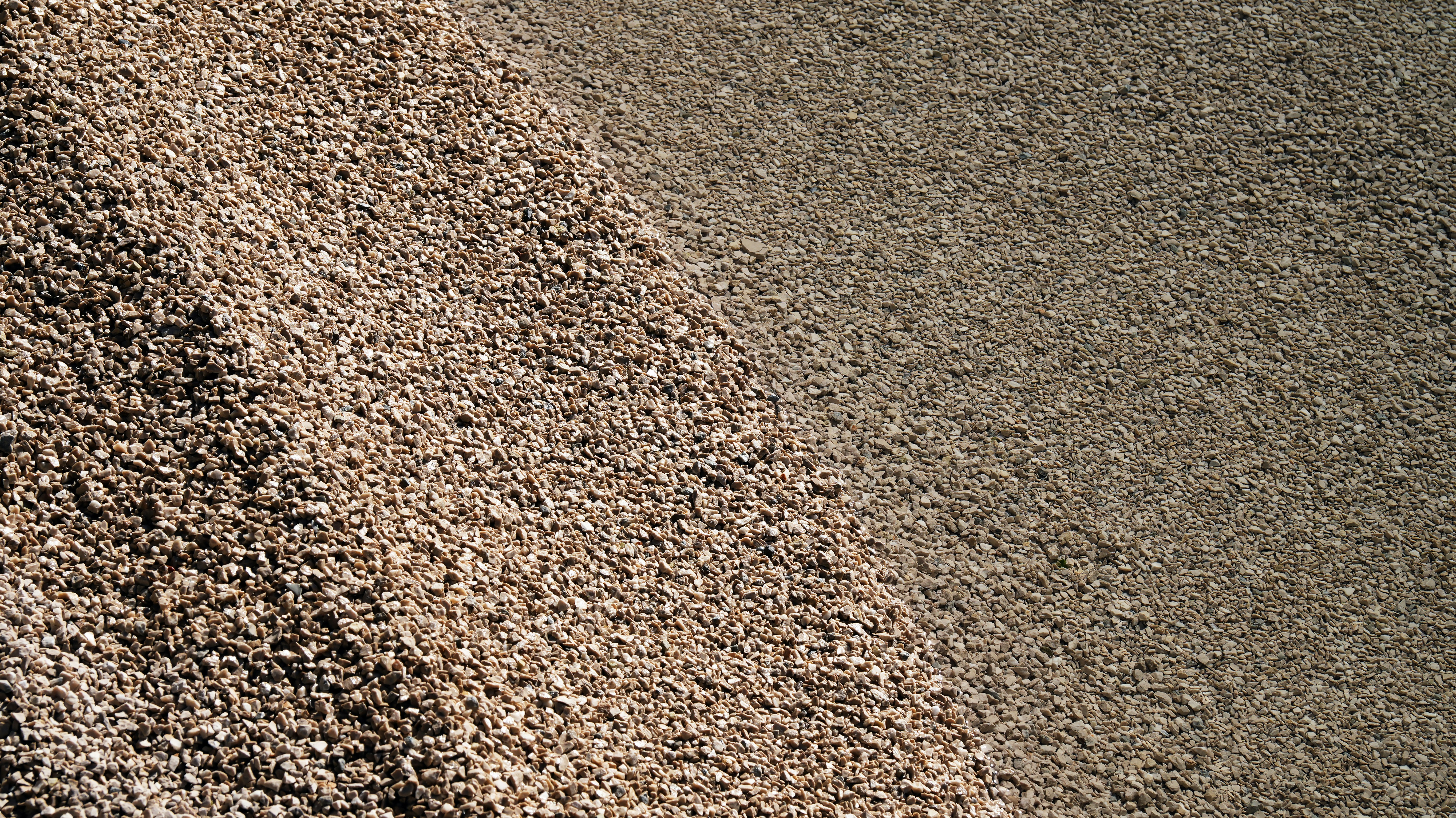 A pile of light brown gravel beside a flat area of smaller pebbles