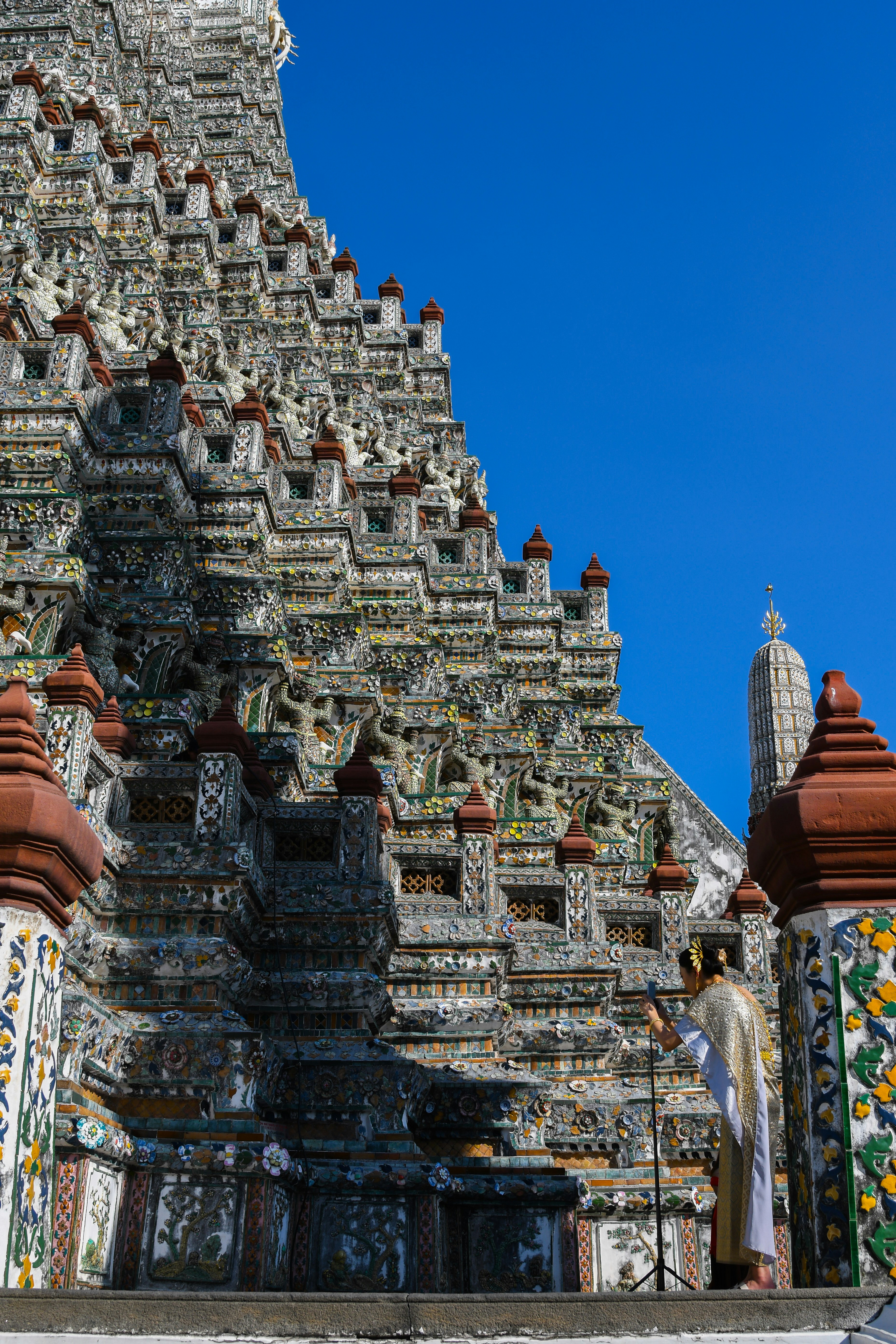 Una persona in abiti tradizionali thailandesi che scatta una foto al Wat Arun di Bangkok