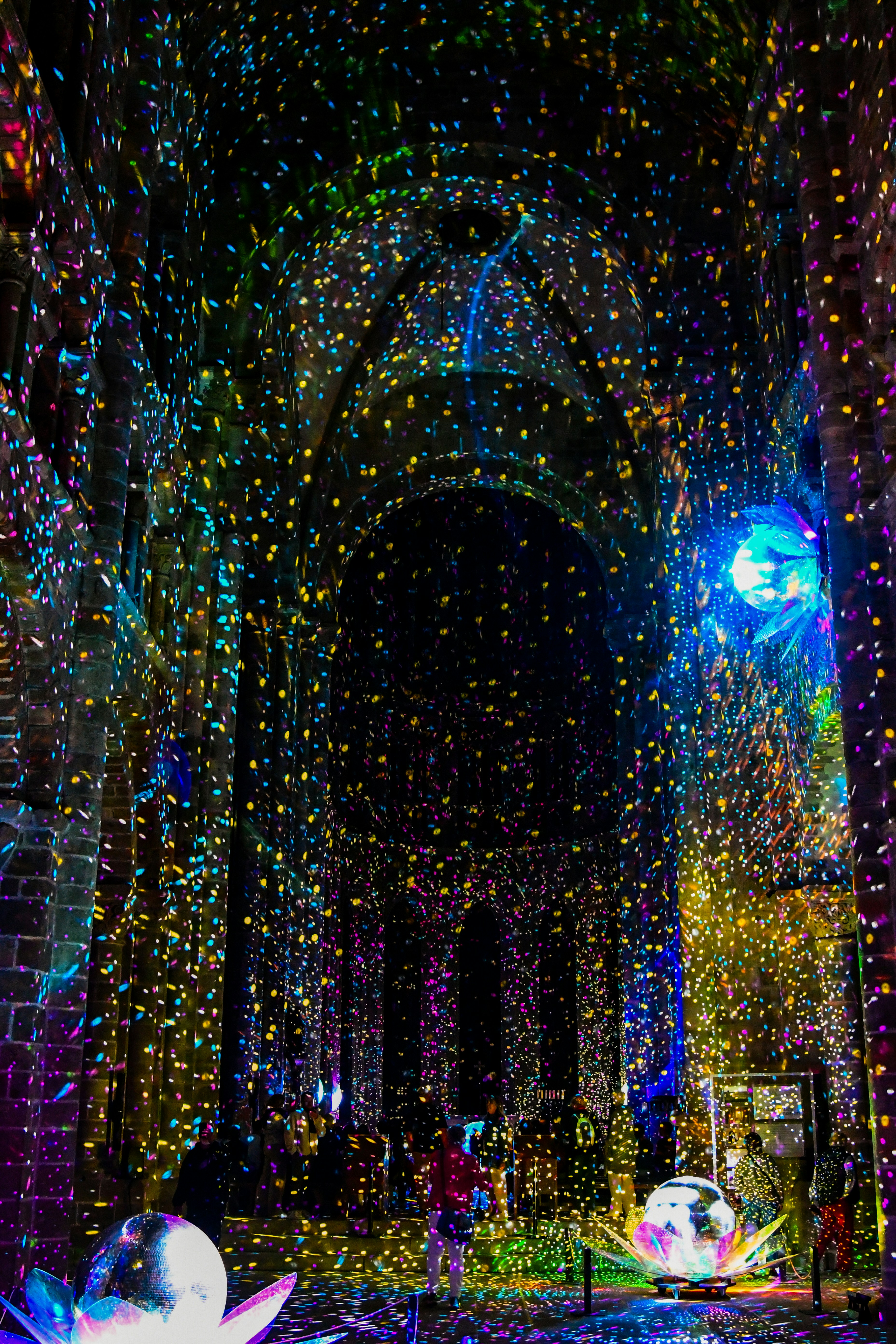 Proiezioni di luce colorate che si riflettevano sulle pareti e sul soffitto di pietra di un interno oscuro di una cattedrale