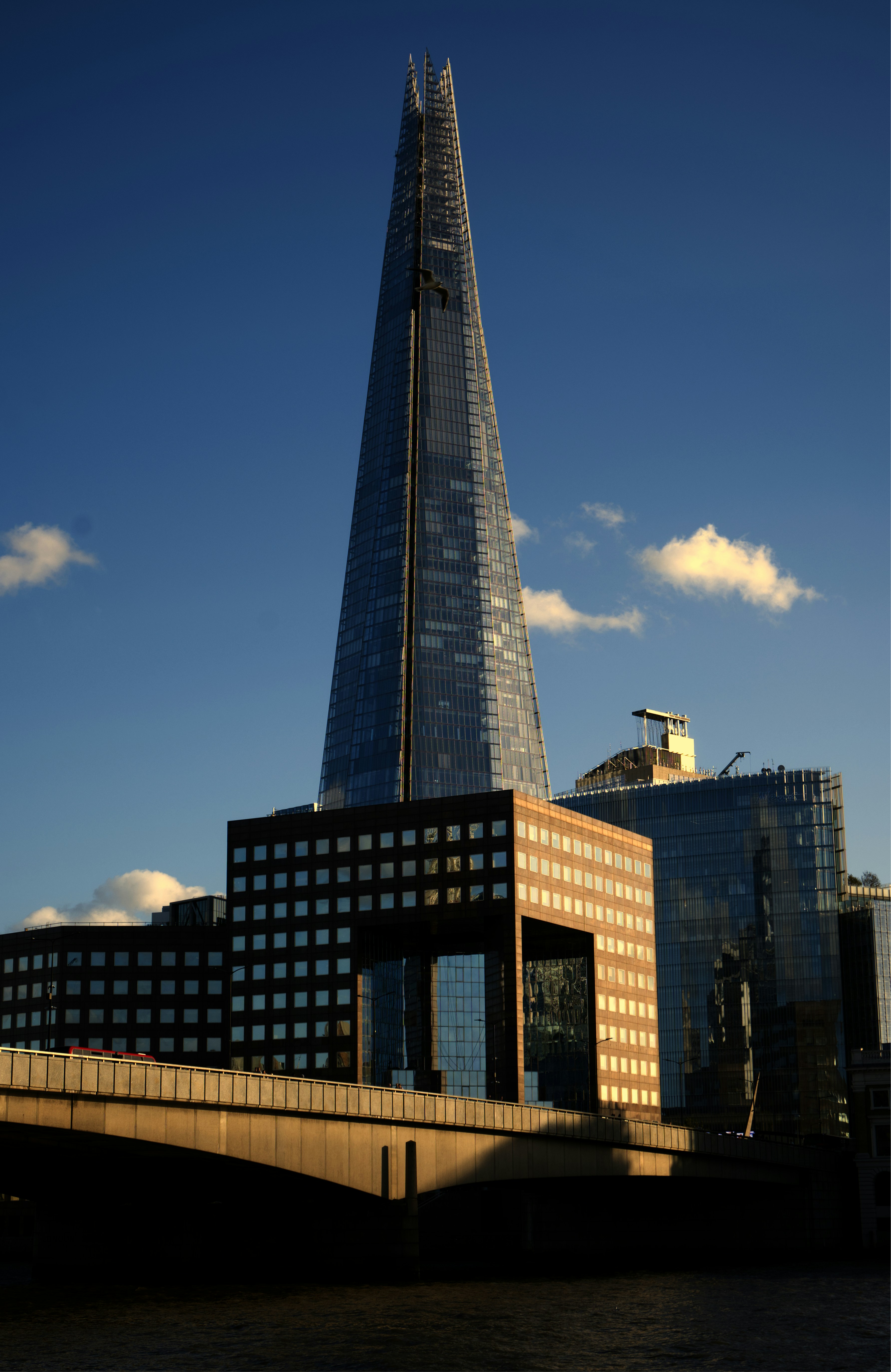 The Shard skyscraper rising above London Bridge and surrounding office buildings under a deep blue sky
