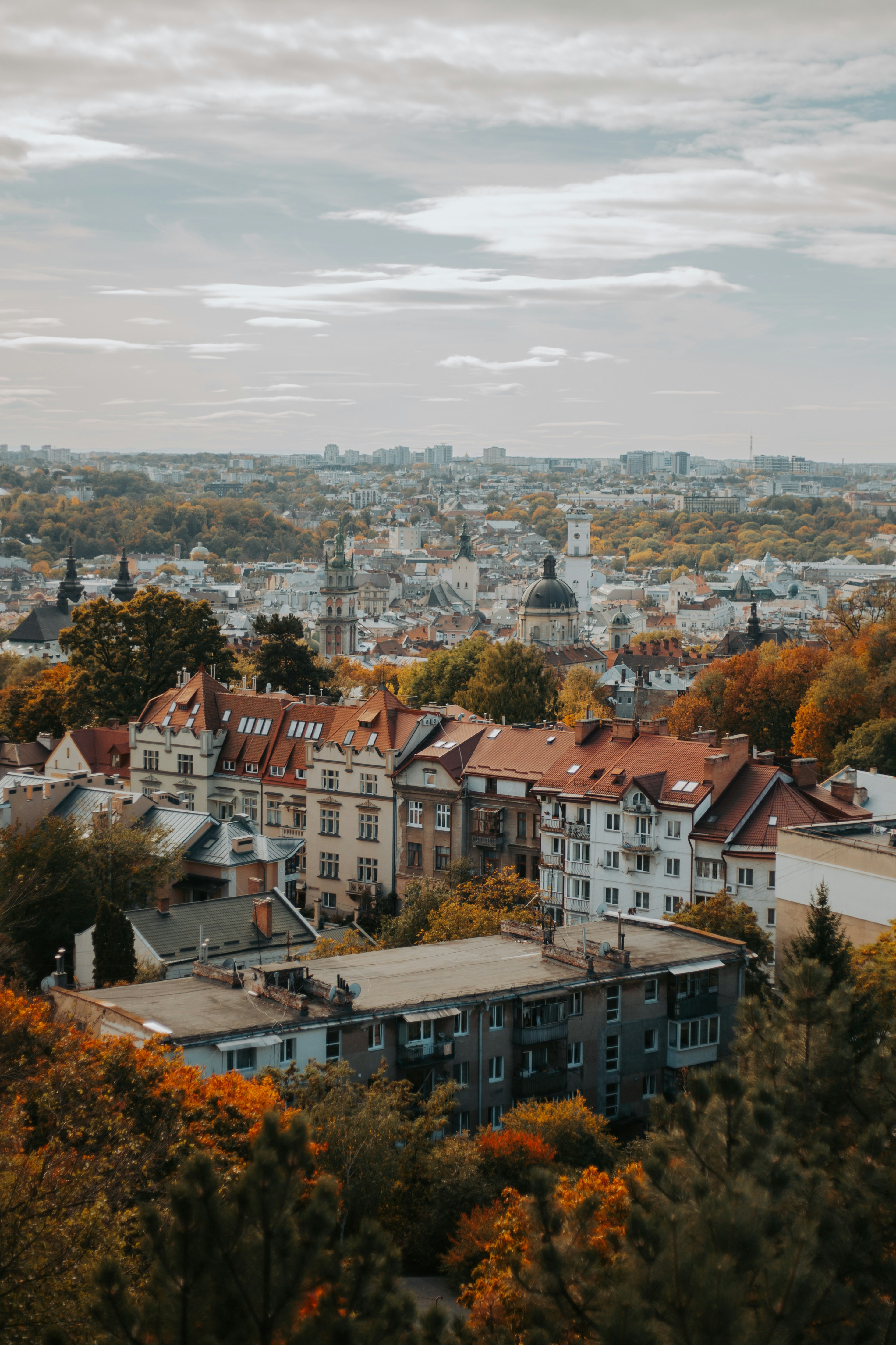 An aerial view of Lviv with historic buildings and autumn trees under a cloudy sky