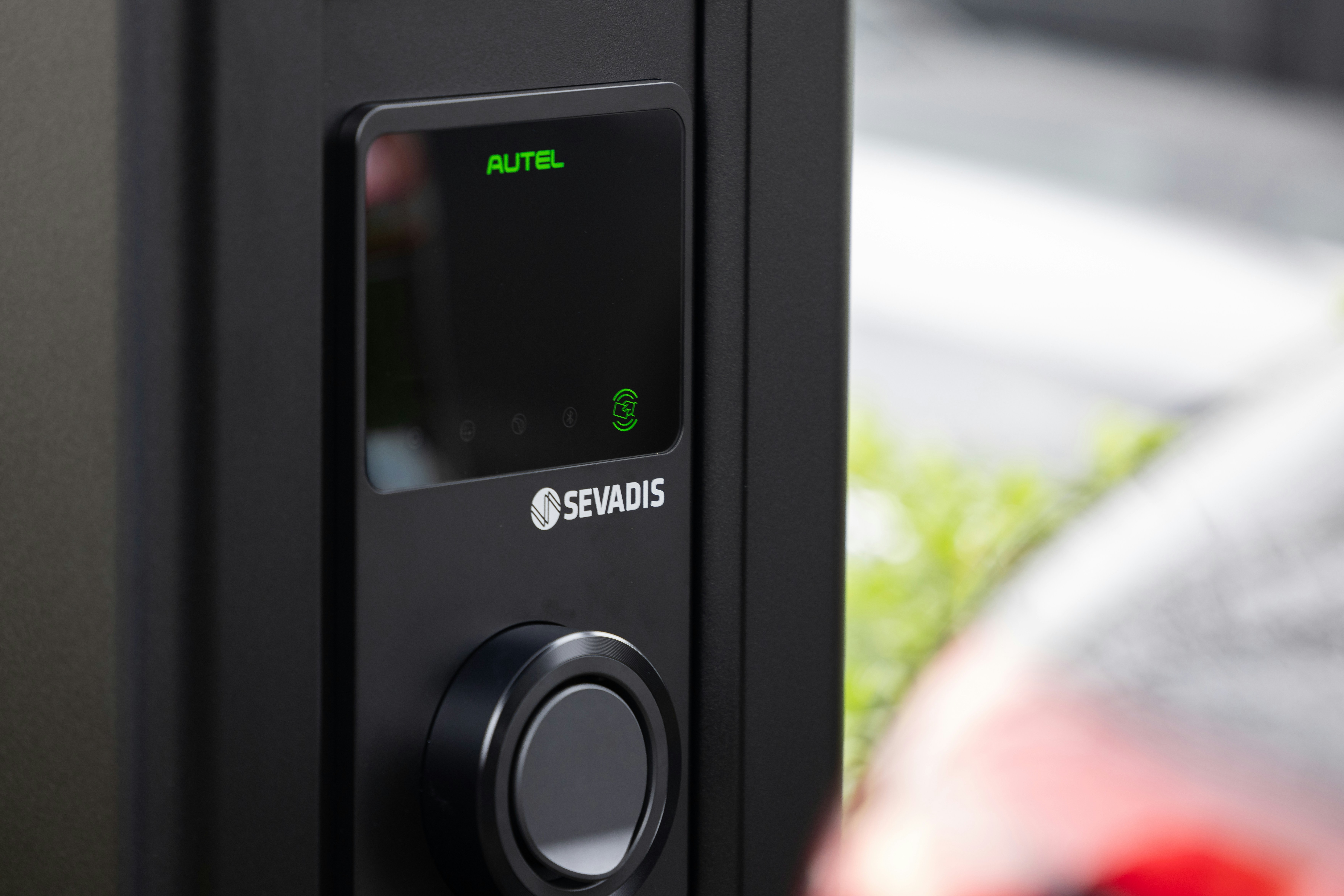 A black electric vehicle charging station with a digital display and a circular control knob