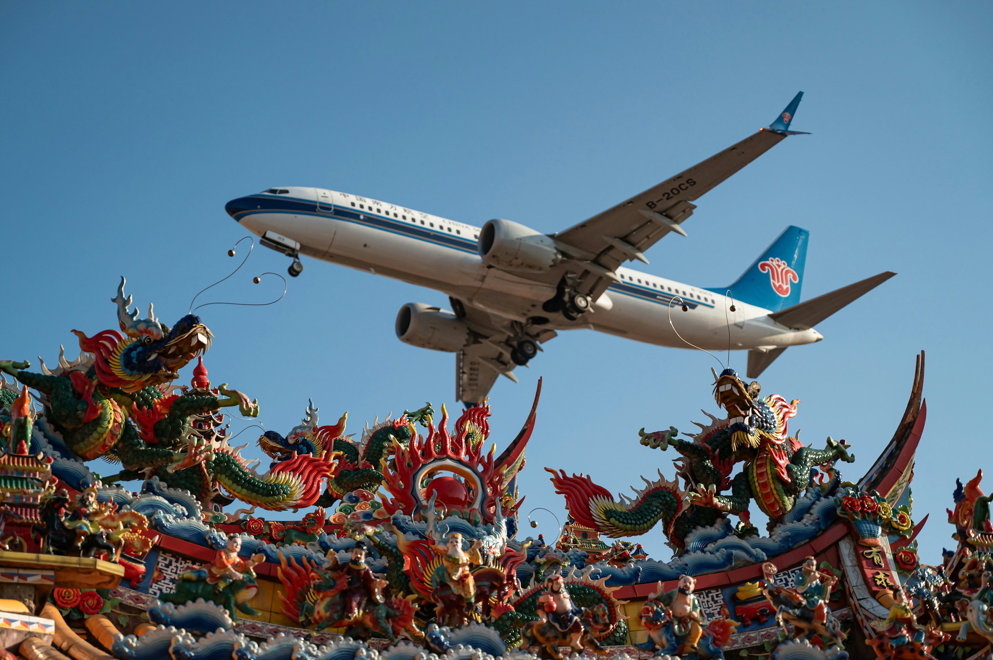 Airplane flying over traditional temple roof - Free Photo on Unsplash