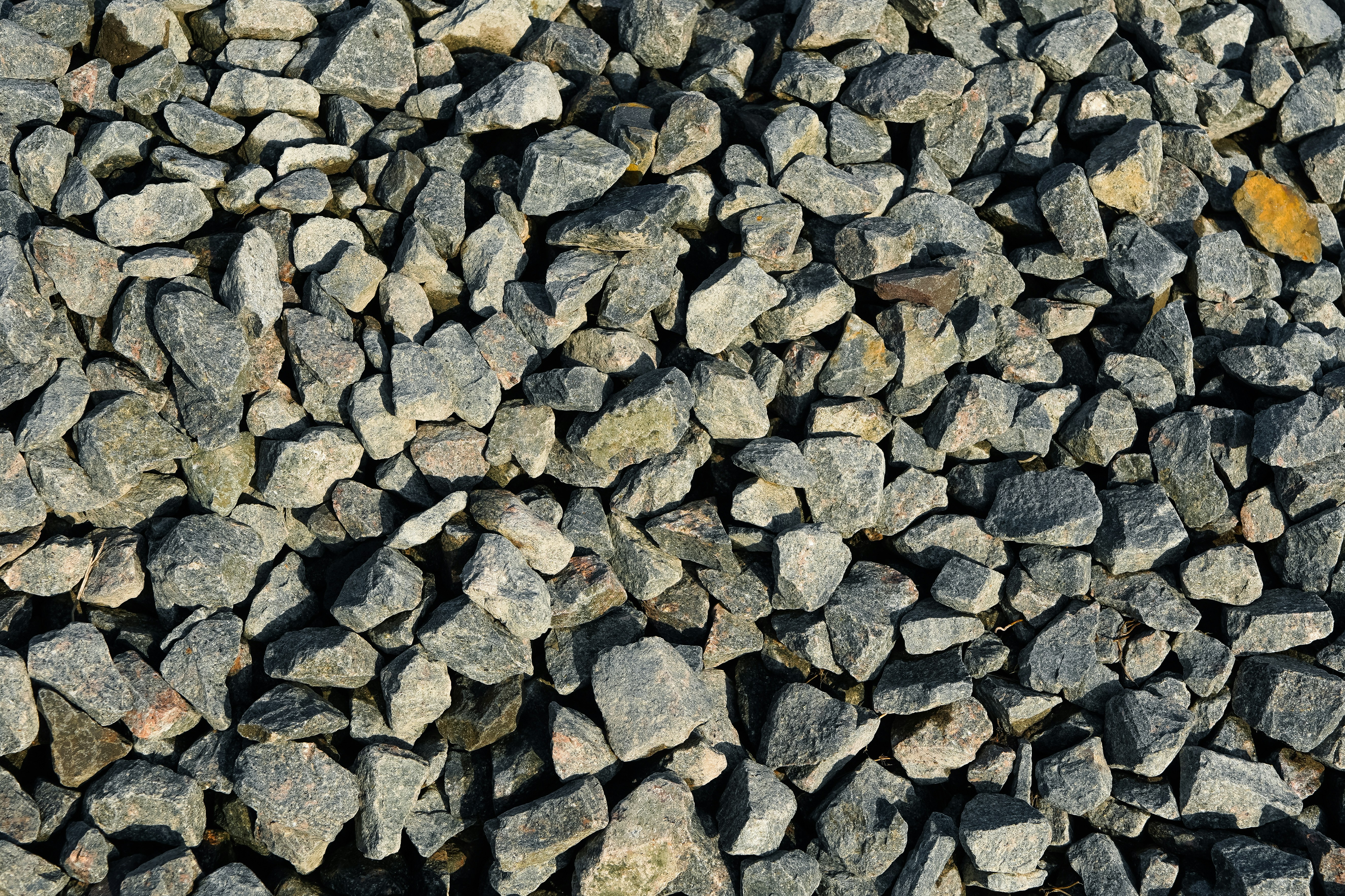 A pile of jagged grey crushed rocks with a single yellow stone